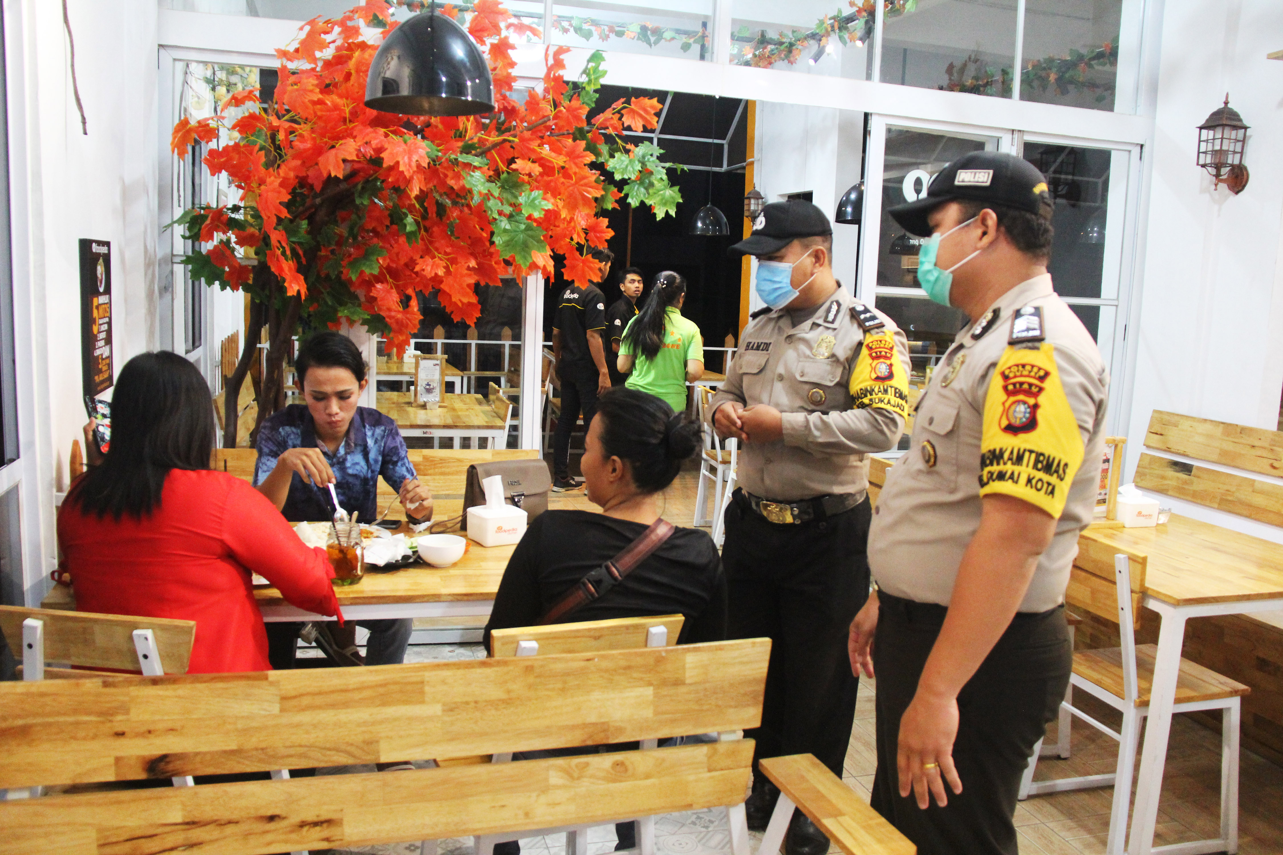 Anggota kepolisian memberikan imbauan kepada sejumlah pengunjung kafe agar tidak berkumpul untuk mencegah terjangkit wabah COVID-19.