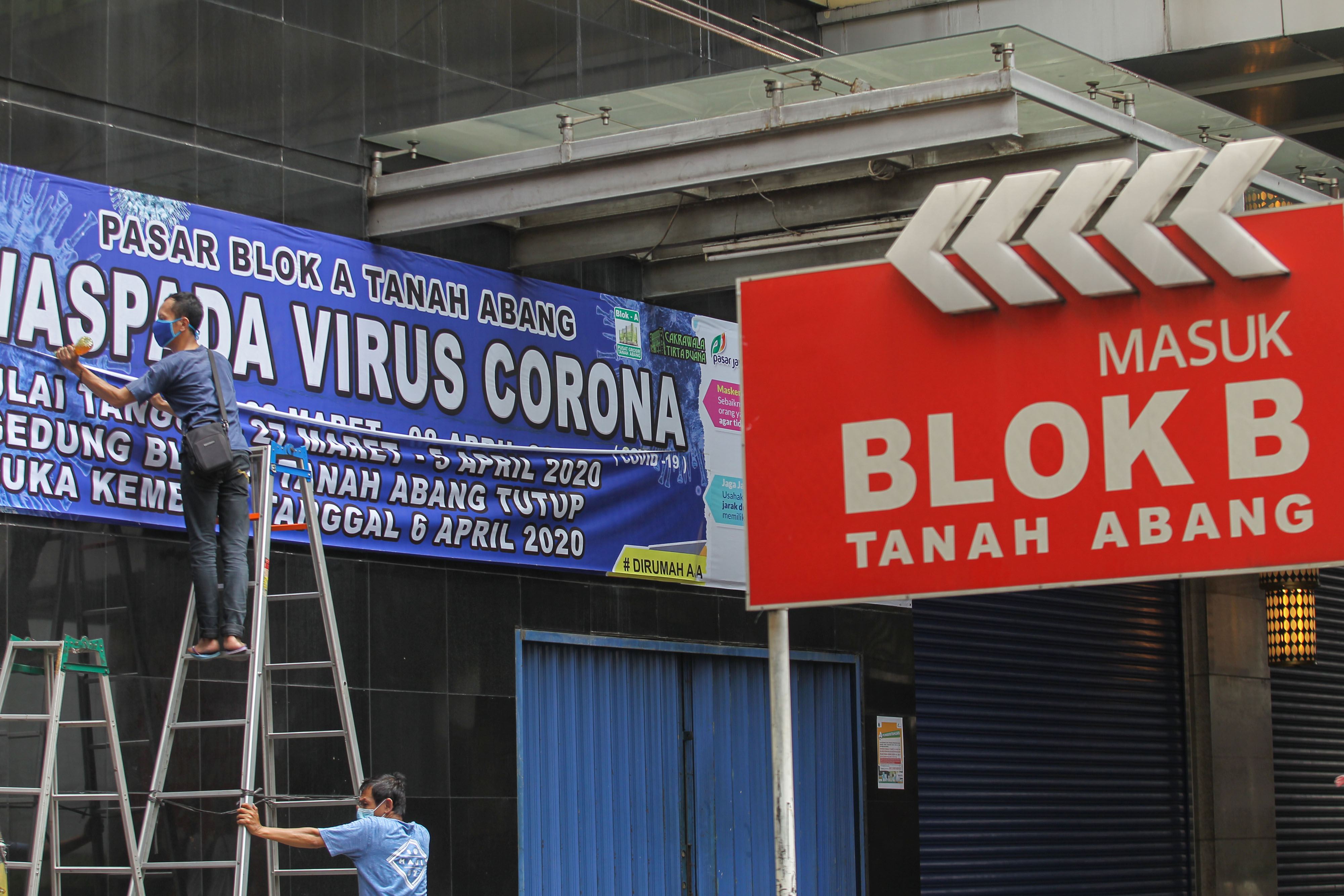 Petugas memasang spanduk pengumuman penutupan Blok B Pasar Tanah Abang akibat covid-19.