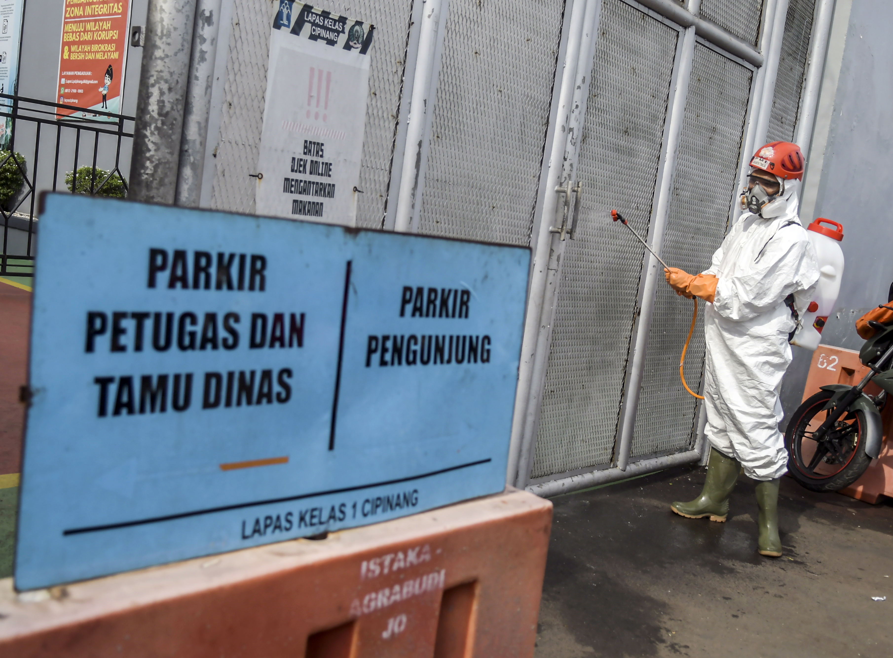 Petugas PMI menyemprotkan cairan disinfektan di pintu Lembaga Pemasyarakatan Kelas 1 Cipinang, Jakarta.