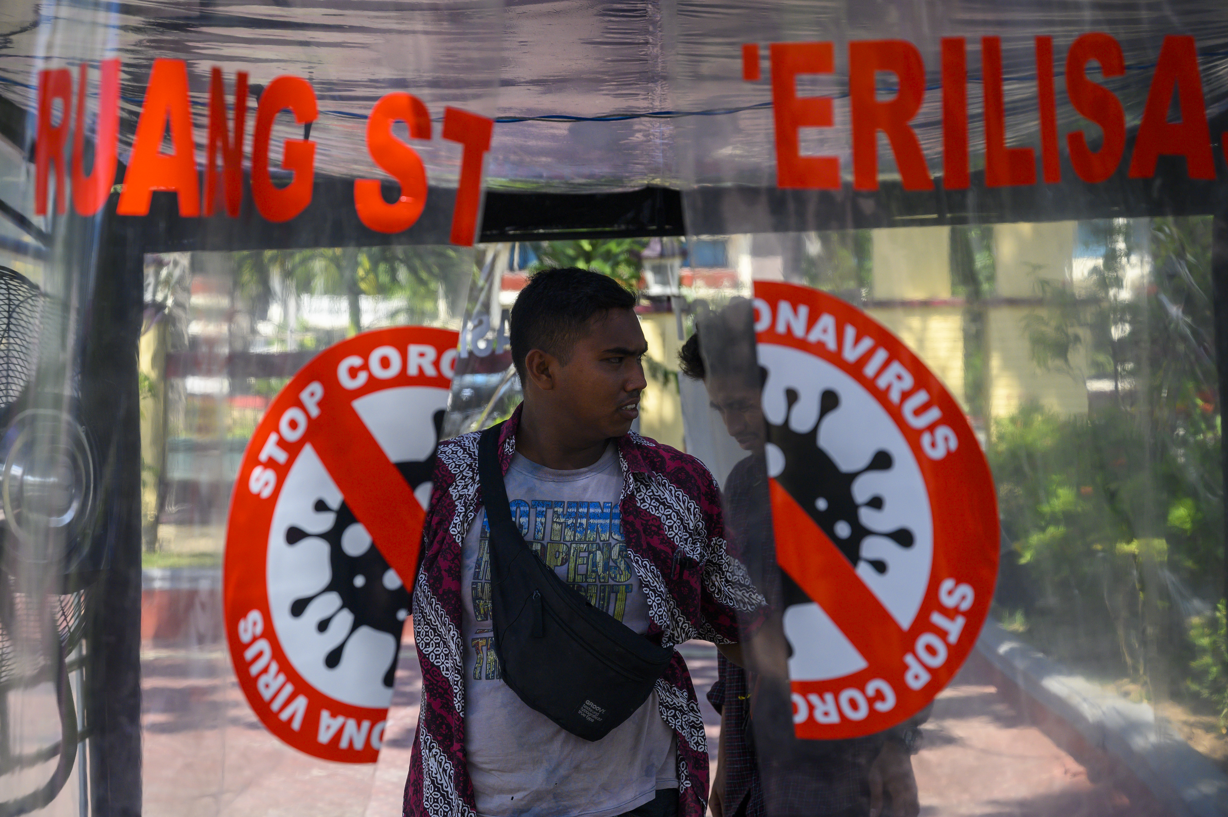 Seorang pengunjung berjalan keluar setelah disemprot disinfektan di dalam bilik sterilisasi di halaman Mapolda Sulteng, Palu, Sulteng.