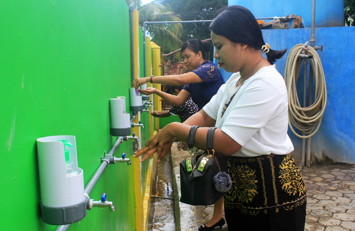 Umat mencuci tangan dulu sebelum beribadah di gereja