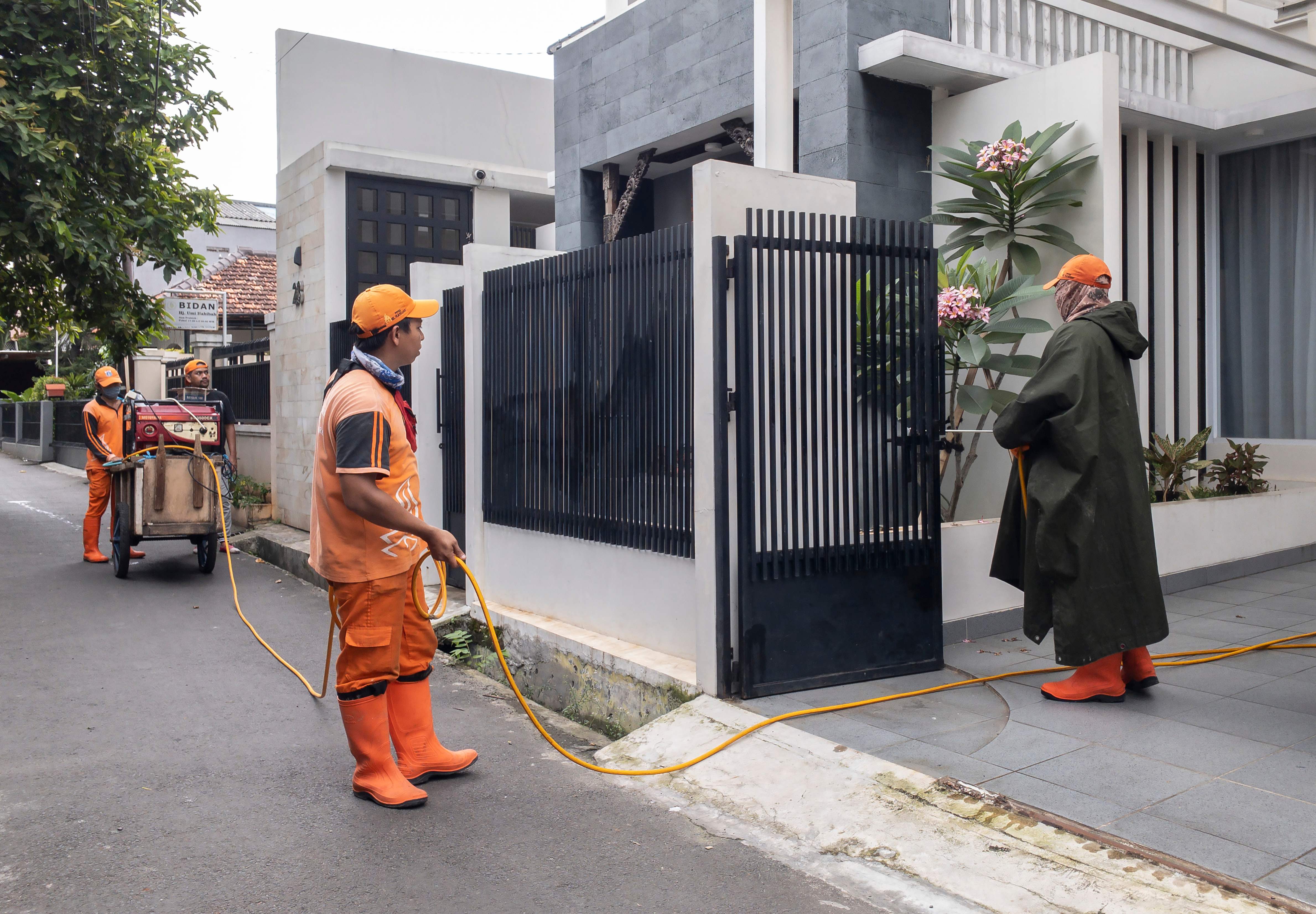 Pekerja menyemprotkan cairan disinfektan di komplek perumahan untuk mencegah penyebaran virus korona.