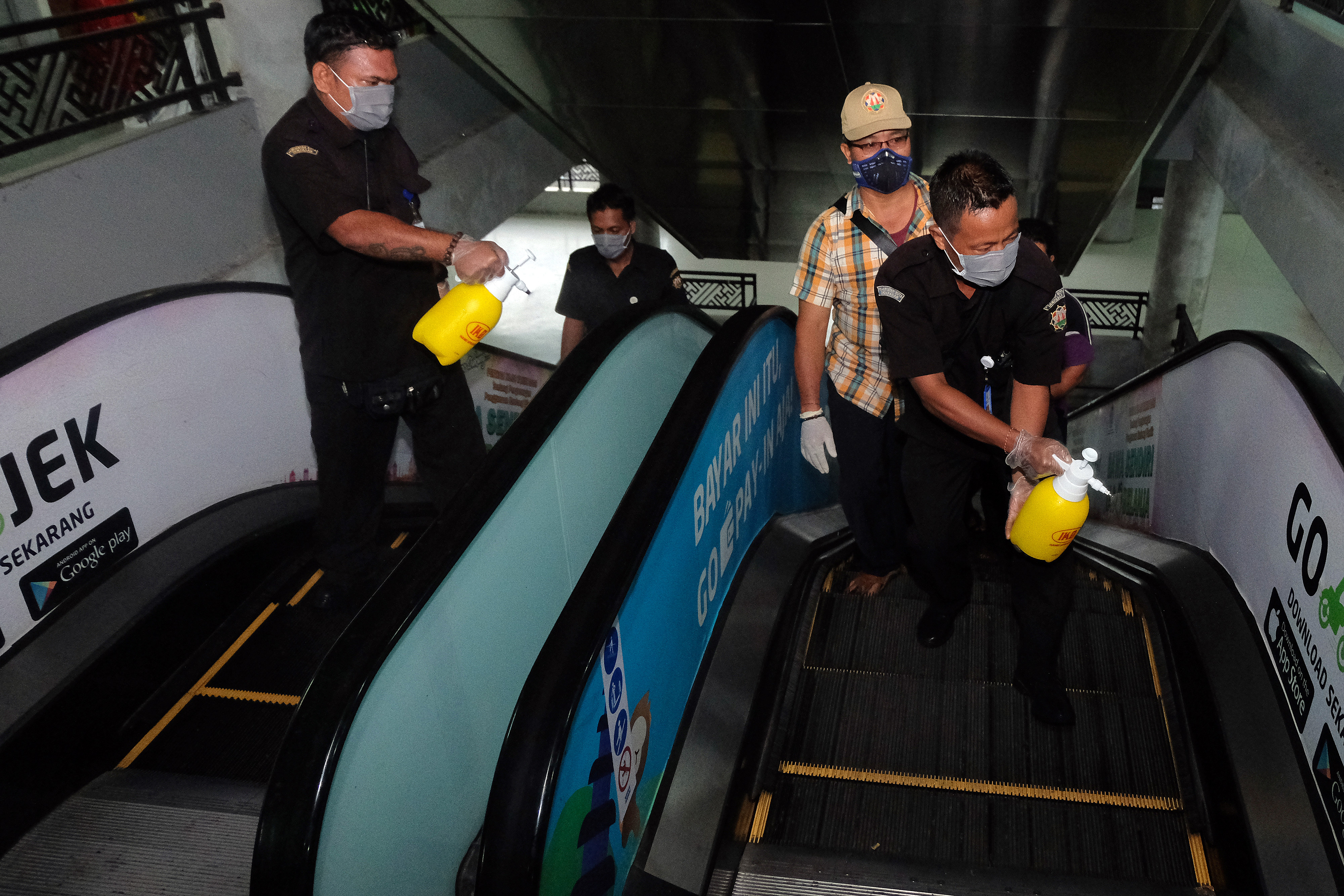 Petugas menyemprotkan disinfektan pada tangga eskalator di Pasar Badung, Denpasar.