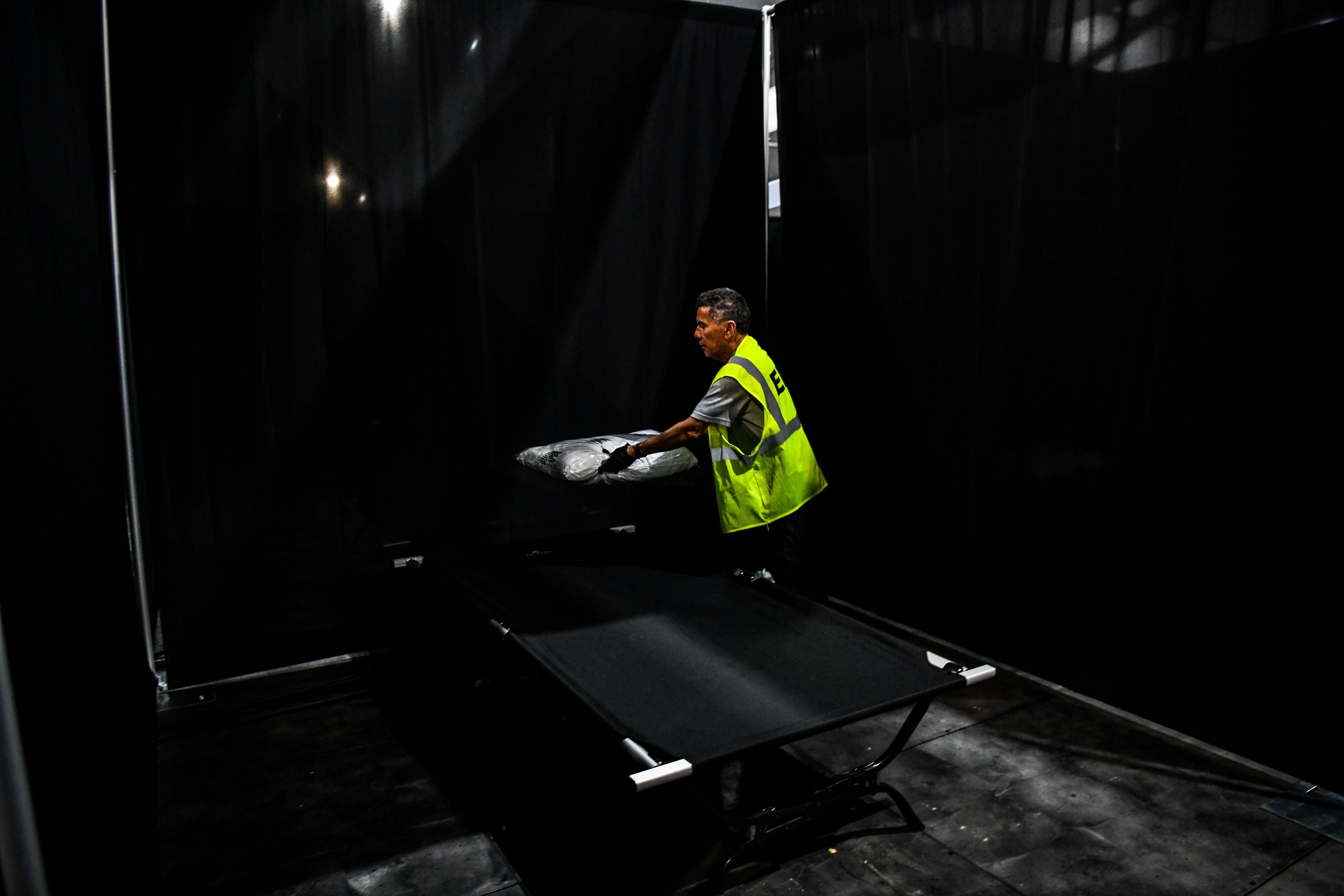 Seorang pekerja meletakkan bantal di tempat tidur di sebuah rumah sakit darurat di Miami, Florida.