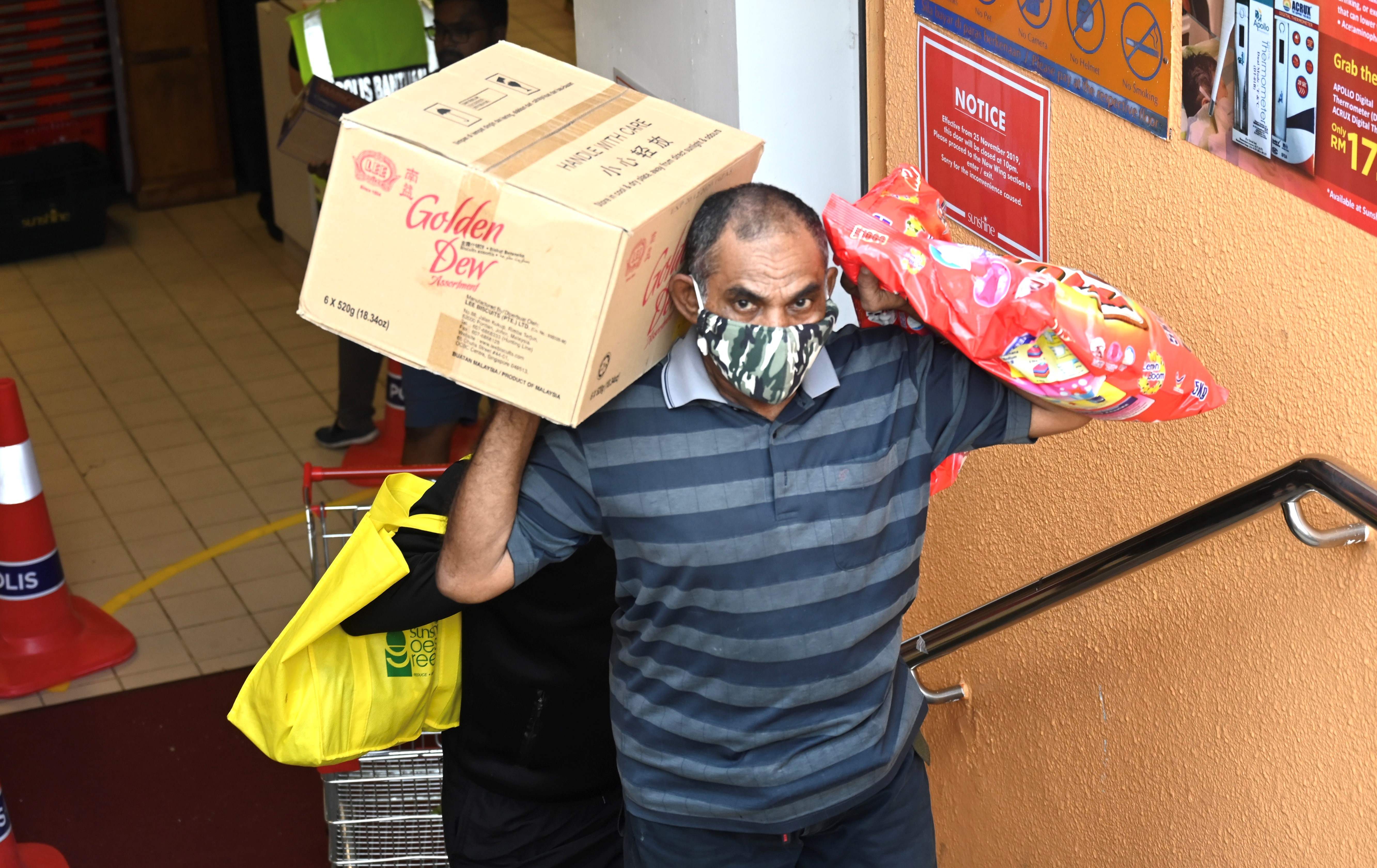 Seseorang membawa belanjaannya dari supermarket selama penutupan sebagian di George Town, Malaysia di tengah kekhawatiran tentang Covid-19.
