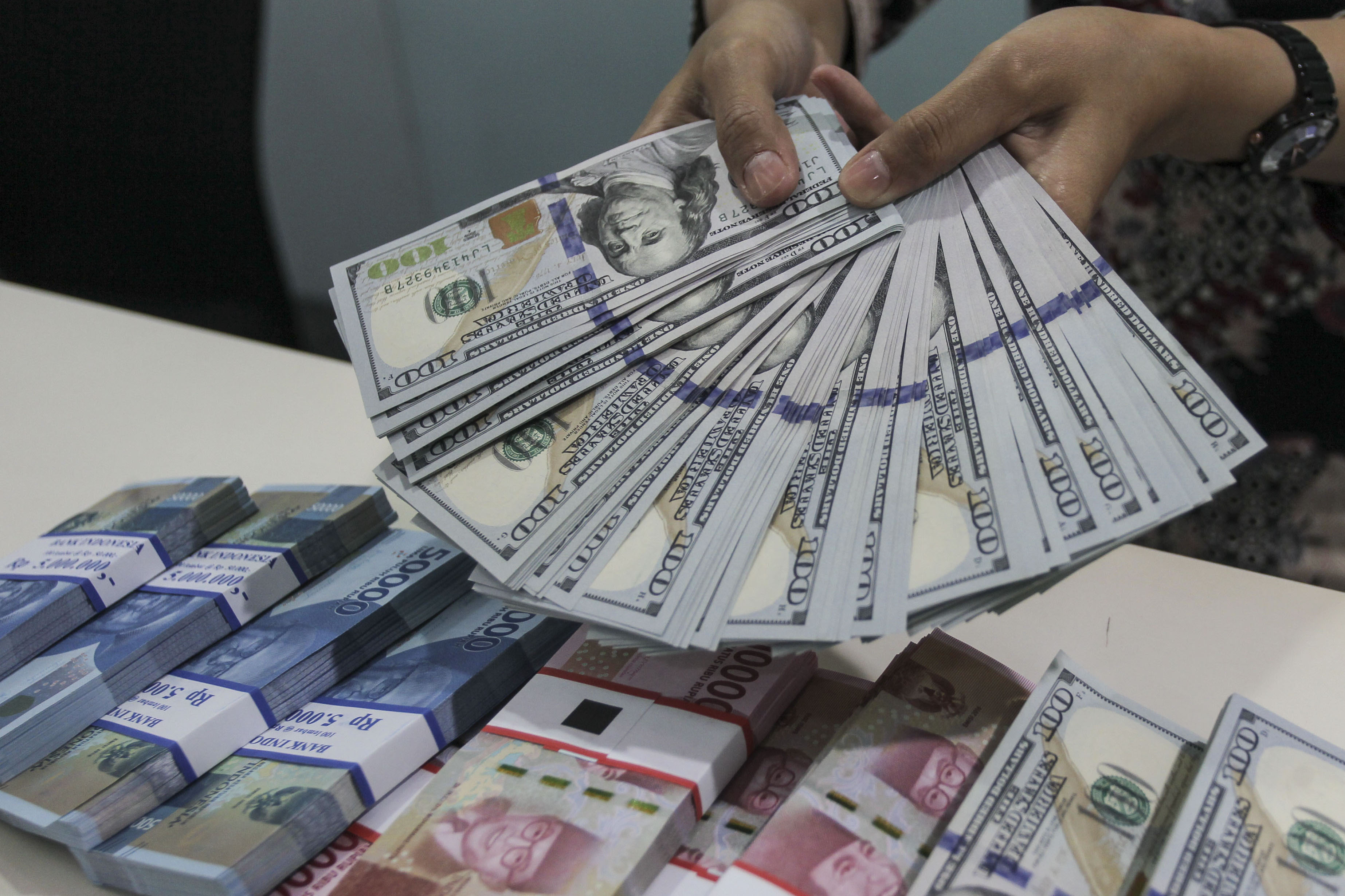 Teller Bank Mandiri menunjukkan uang pecahan Dolar AS dan Rupiah di Bank Mandiri KCP Jakarta DPR, Senin (7/1/2019).