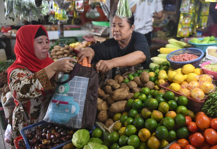 Pedagang memasukkan belanjaan ke dalam tas ramah lingkungan saat bertransaksi di Pasar Tebet Barat, Jakarta.