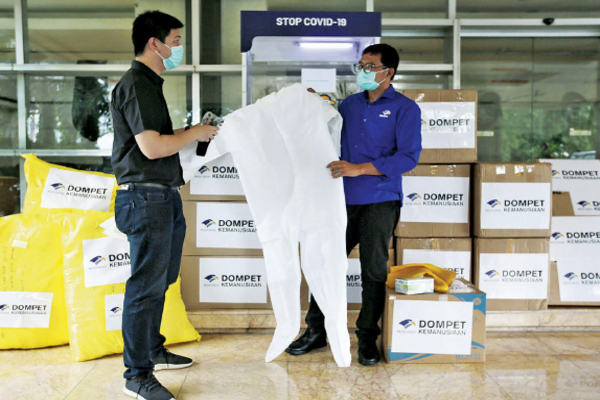 Ketua Yayasan Media Group Ali Sadikin (kanan) menunjukkan alat pelindung diri (APD) hazmat kepada Public Relation Help to Help Raymond