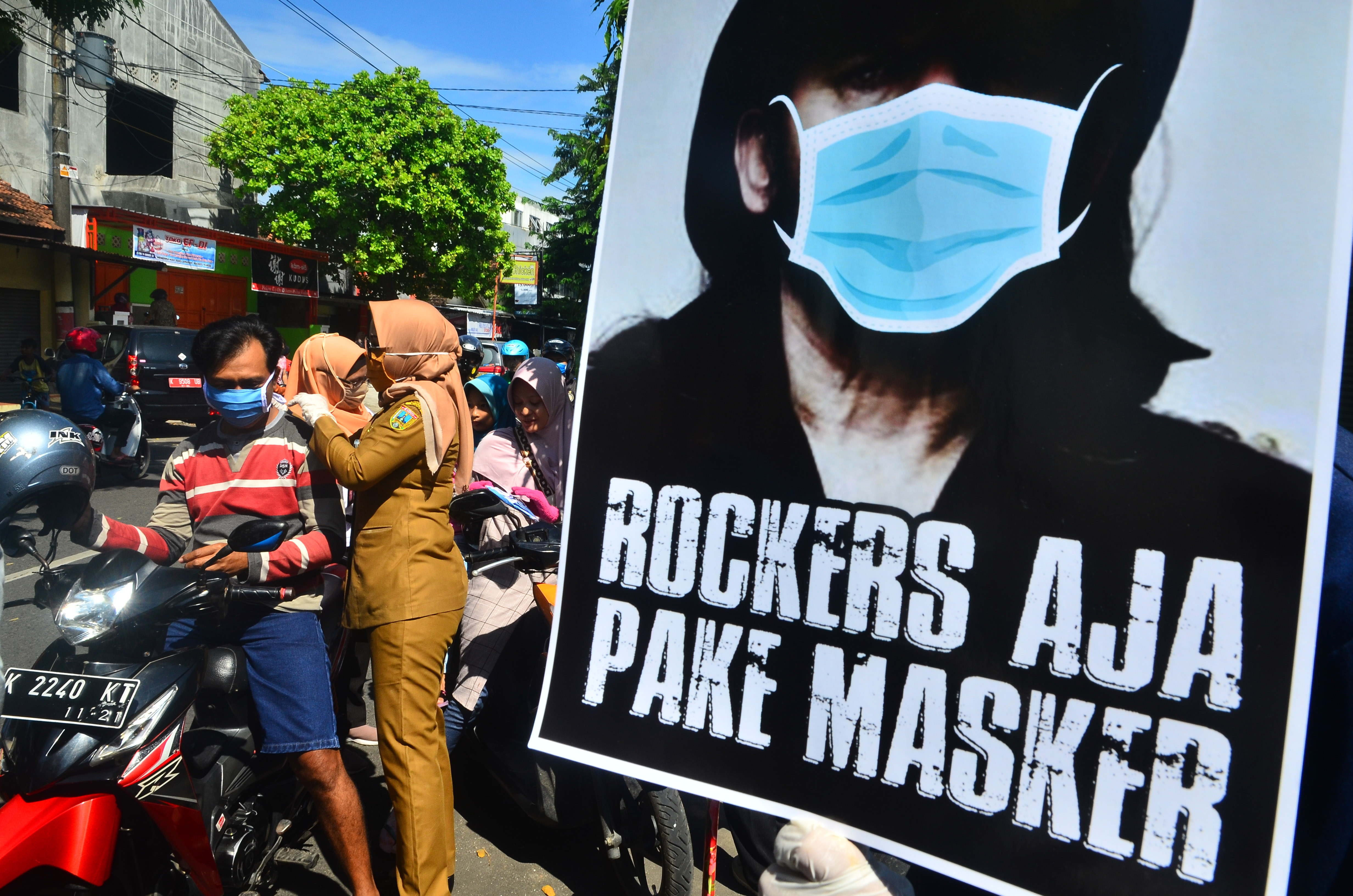 Petugas membagikan masker kepada penguna jalan yang melintas di Kudus, Jawa Tengah, Senin (13/4). 