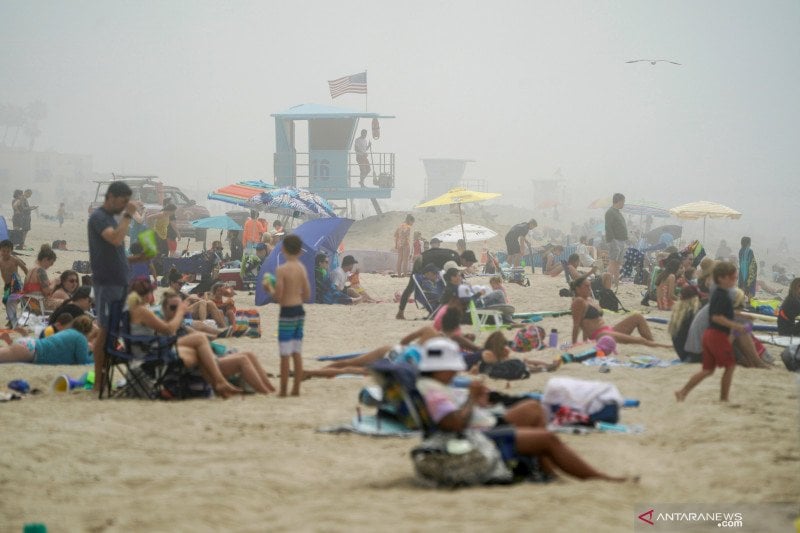 Warga beraktivitas di Pantai Huntington dan sebagian tampak tidak mengenakan masker, dalam masa pandemi  di California.