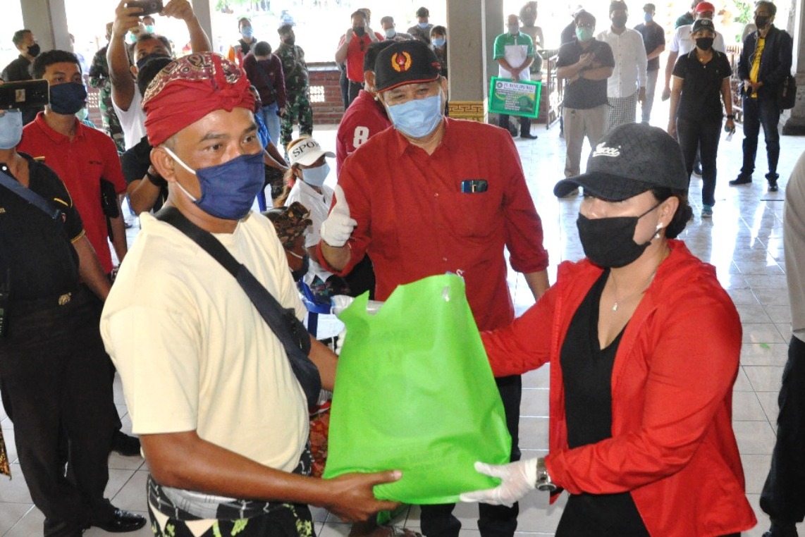 Bupati Tabanan, Bali, Ni Putu Eka Wiryastuti (kanan topi hitam) membagikan paket sembako dan masker kepada warga terdampak pandemi Covid-19.