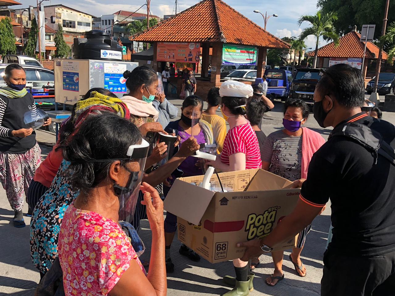 Relawan membagikan masker dan pelindung wajah untuk warga di Kota Denpasar, Bali, Kamis (23/4/2020).