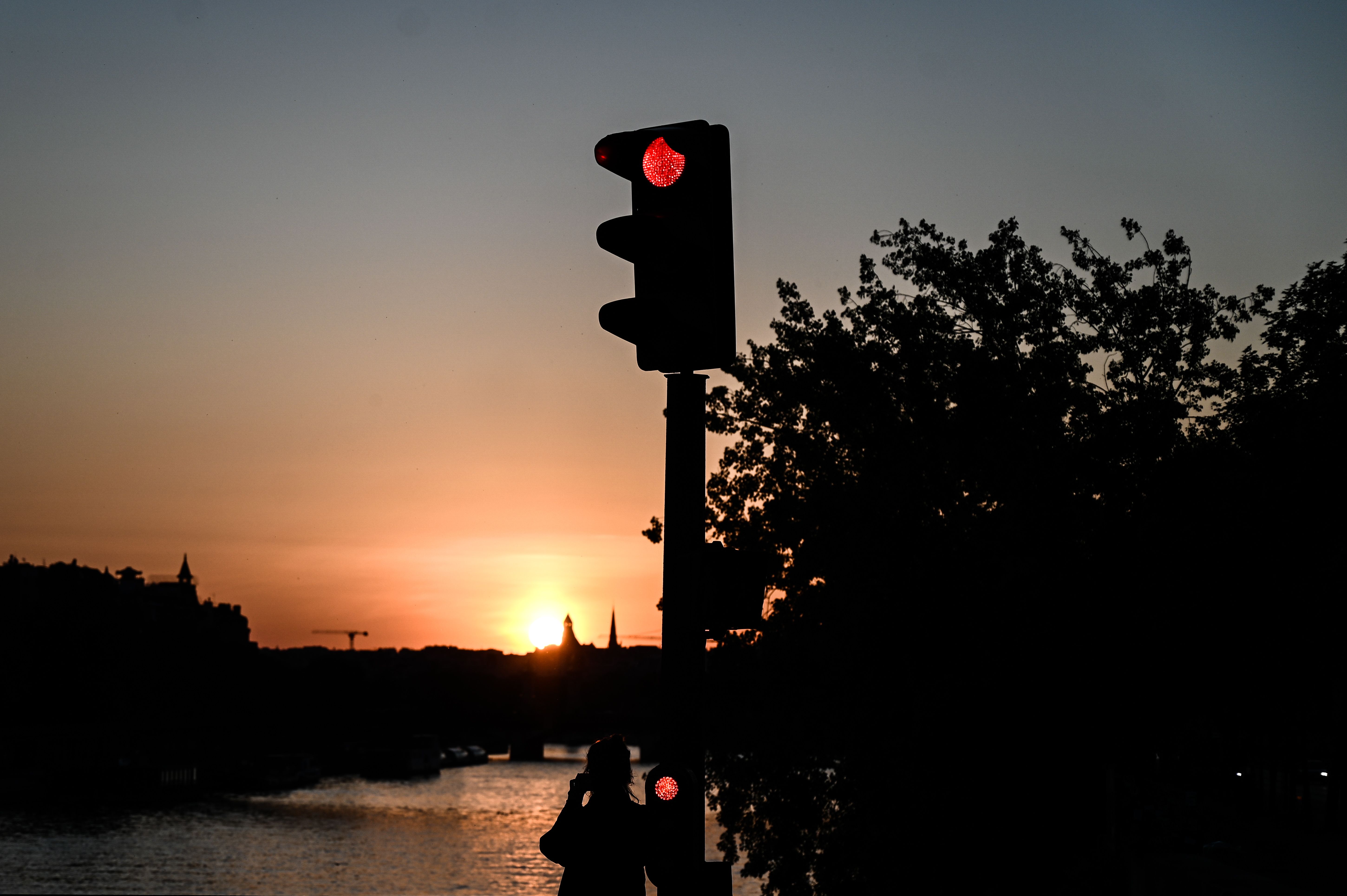 Seorang perempuan membidik matahari tenggelam di tepi Sungai Seine, di Paris, Rabu (22/3). Prancis telah 37 hari menerapkan lockdown wilayah