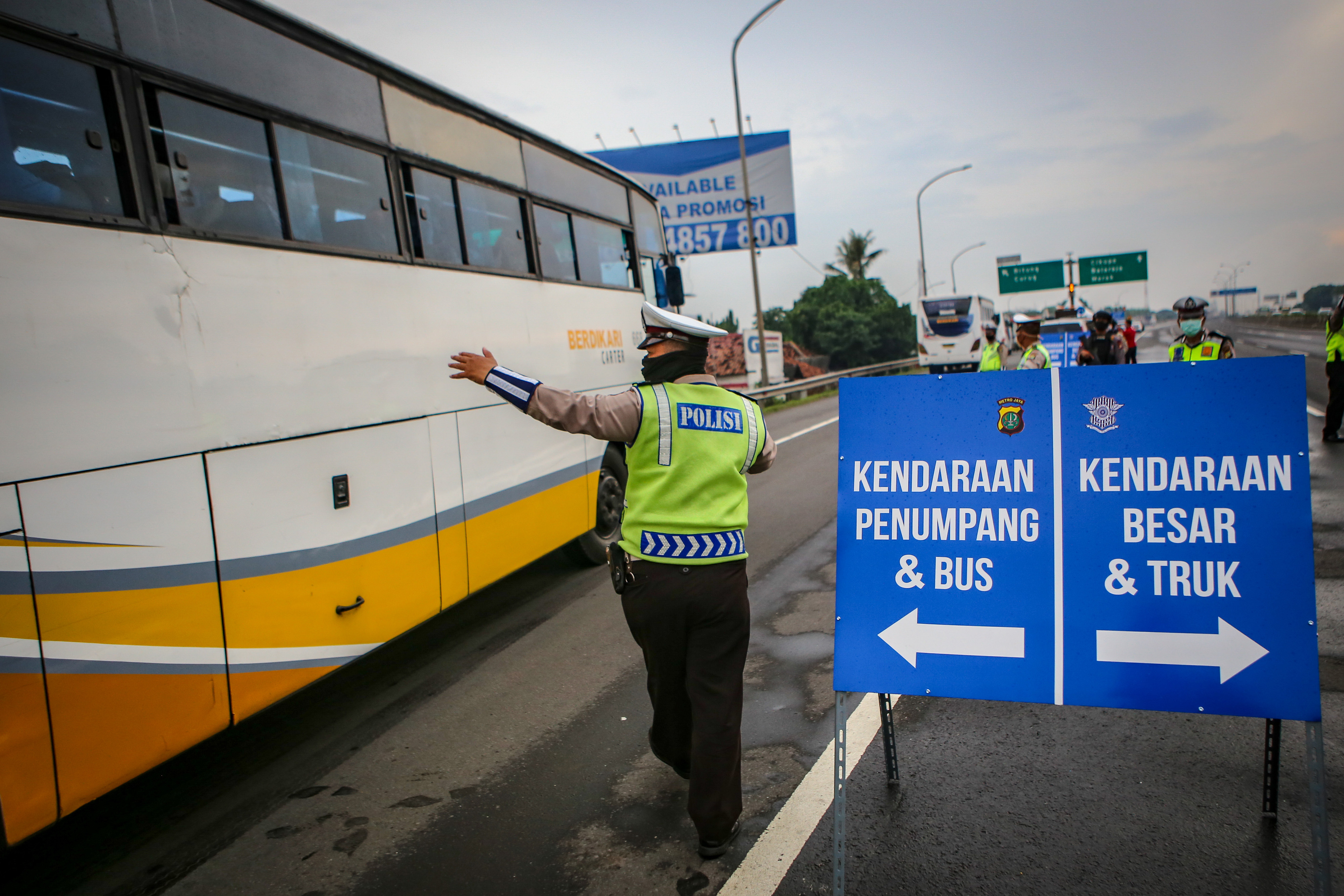 Petugas kepolisian mengarahkan kendaraan umum ke pintu keluar Tol Bitung, Kabupaten Tangerang, Banten, Jumat (24/4). 
