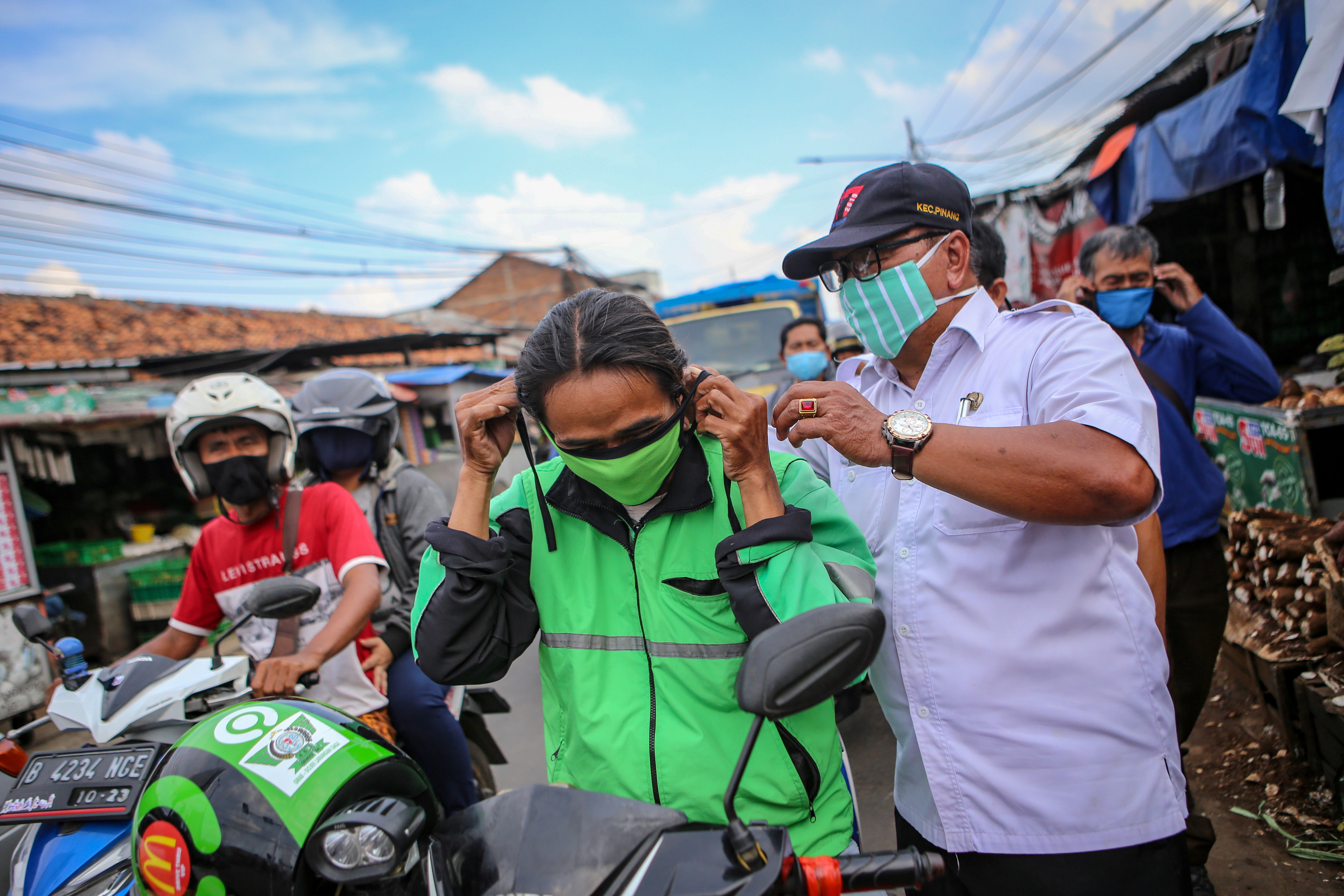 Petugas Kecamatan Pinang membagikan masker berbahan kain kepada sejumlah pengendara motor di Pinang, Kota Tangerang, Banten, Rabu (8/4/2020)