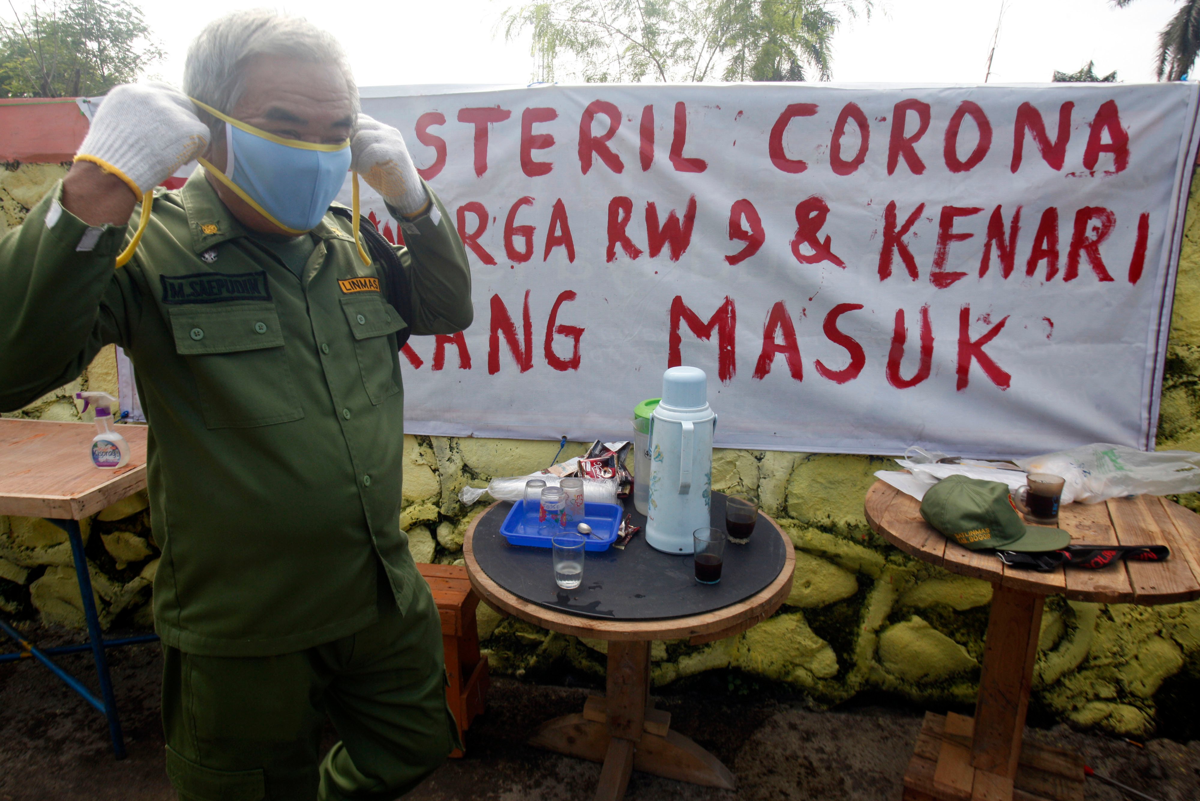 Petugas RW siaga melintas di depan spanduk himbauan streril COVID-19 di kawasan RW Siaga, Desa Palasari, Citeureup, Kabupaten Bogor.