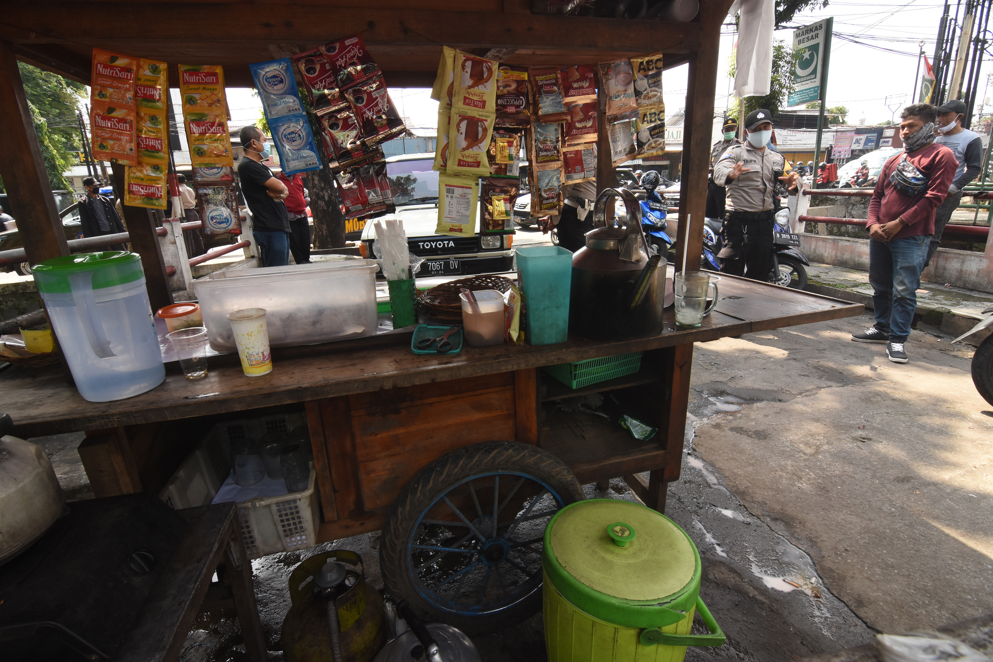 Polisi memberikan imbauan kepada pedagang di tepi jalan saat patroli Pembatasan Sosial Berskala Besar (PSBB) di Jakarta, Jumat (17/4).