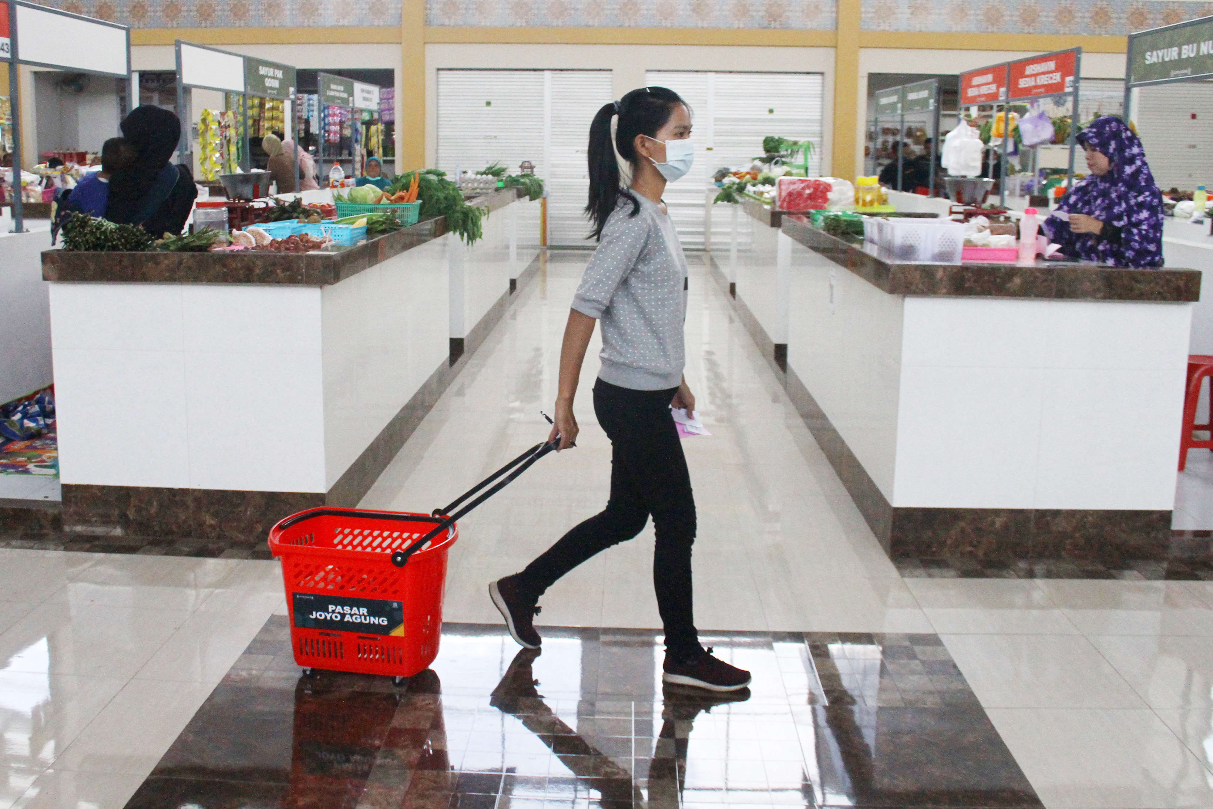 Seorang operator belanja membelikan kebutuhan pangan konsumen di pasar Joyoaagung, Malang, Jawa Timur, Senin (30/3).