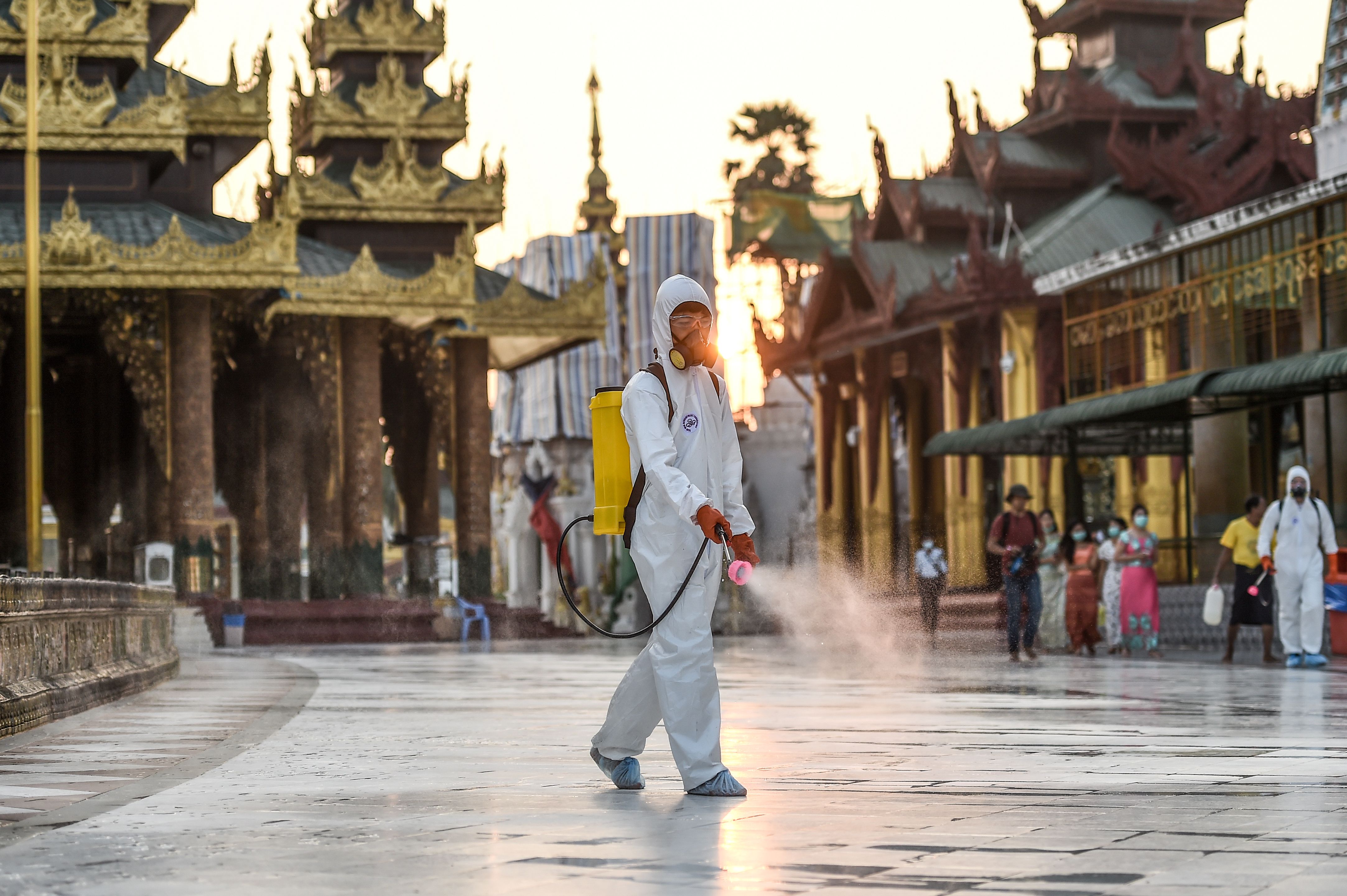 Petugas menyemprotkan disinfektan di komplek Pagoda Shwedagon di Yangon, Myanmar.