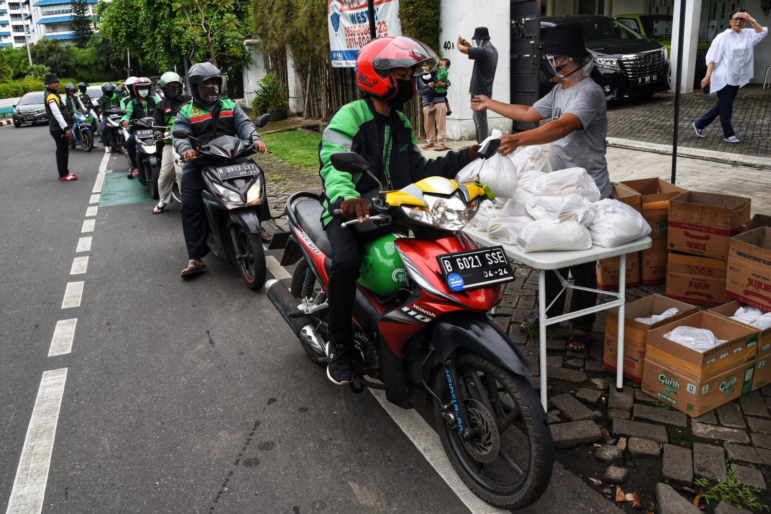 Seorang warga membagikan sembako secara swadaya untuk pengemudi ojek daring di kawasan Jakarta Selatan.