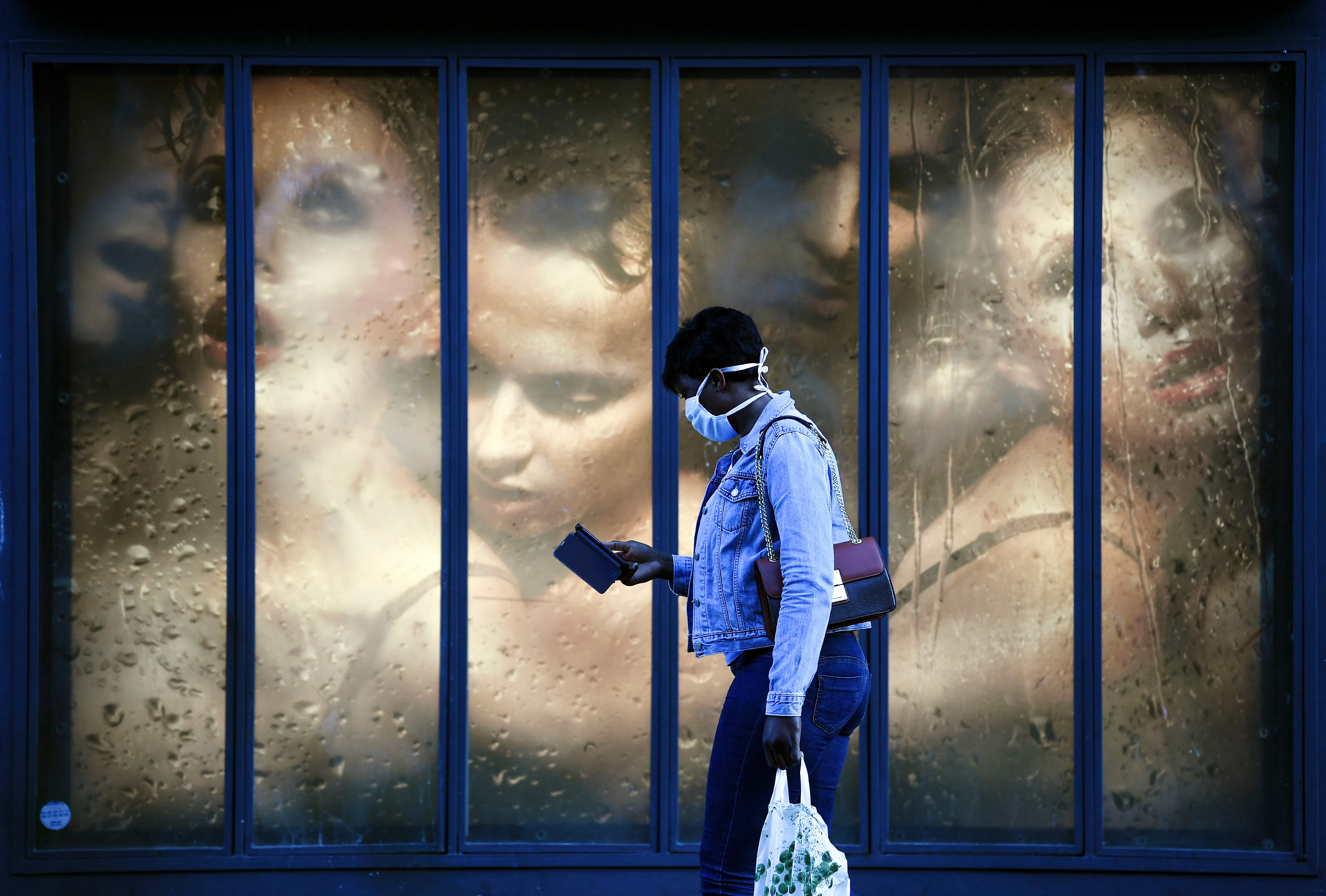 Warga mengenakan masker melintas di depan jendela toko di Paris, Prancis.