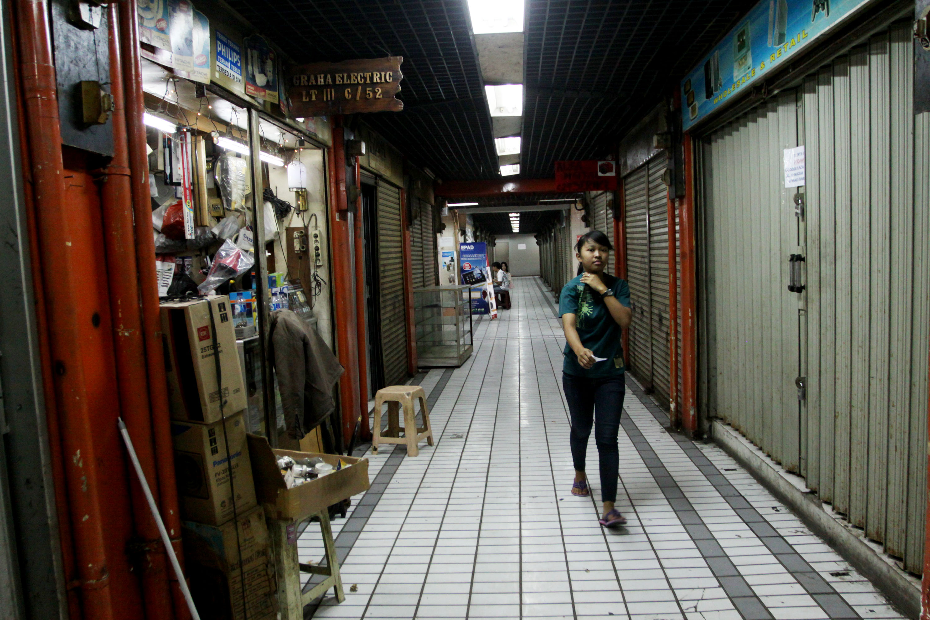 Pengunjung melintas di antara toko yang tutup di Pusat perbelanjaan elektronik Harco Glodok, Jalan Hayam Wuruk, Jakarta, Senin (21/10).