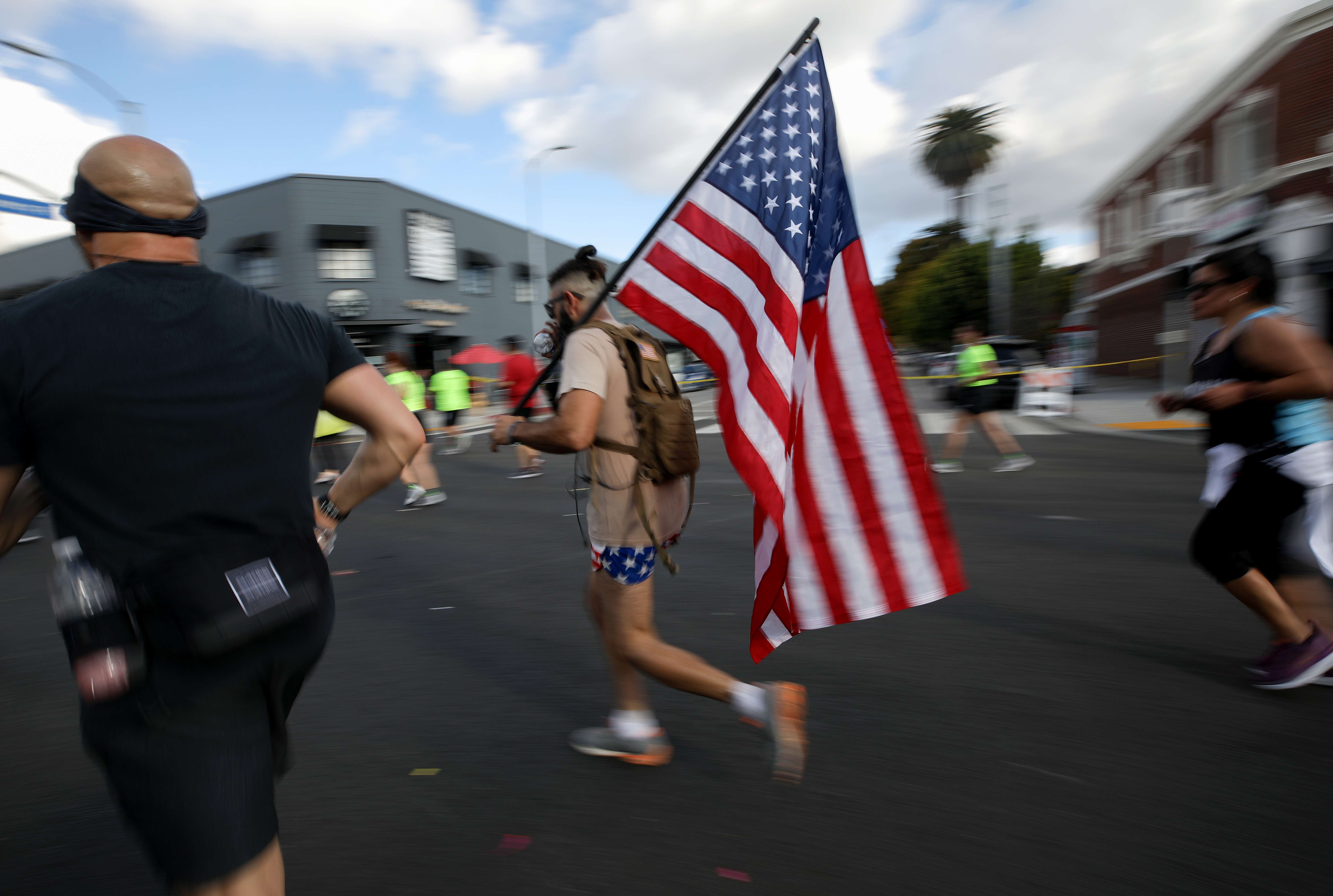 Seorang pelari membawa bendera Amerika Serikat dalam Los Angeles Maraton di tengah kekhawatiran pandemi covid-19.