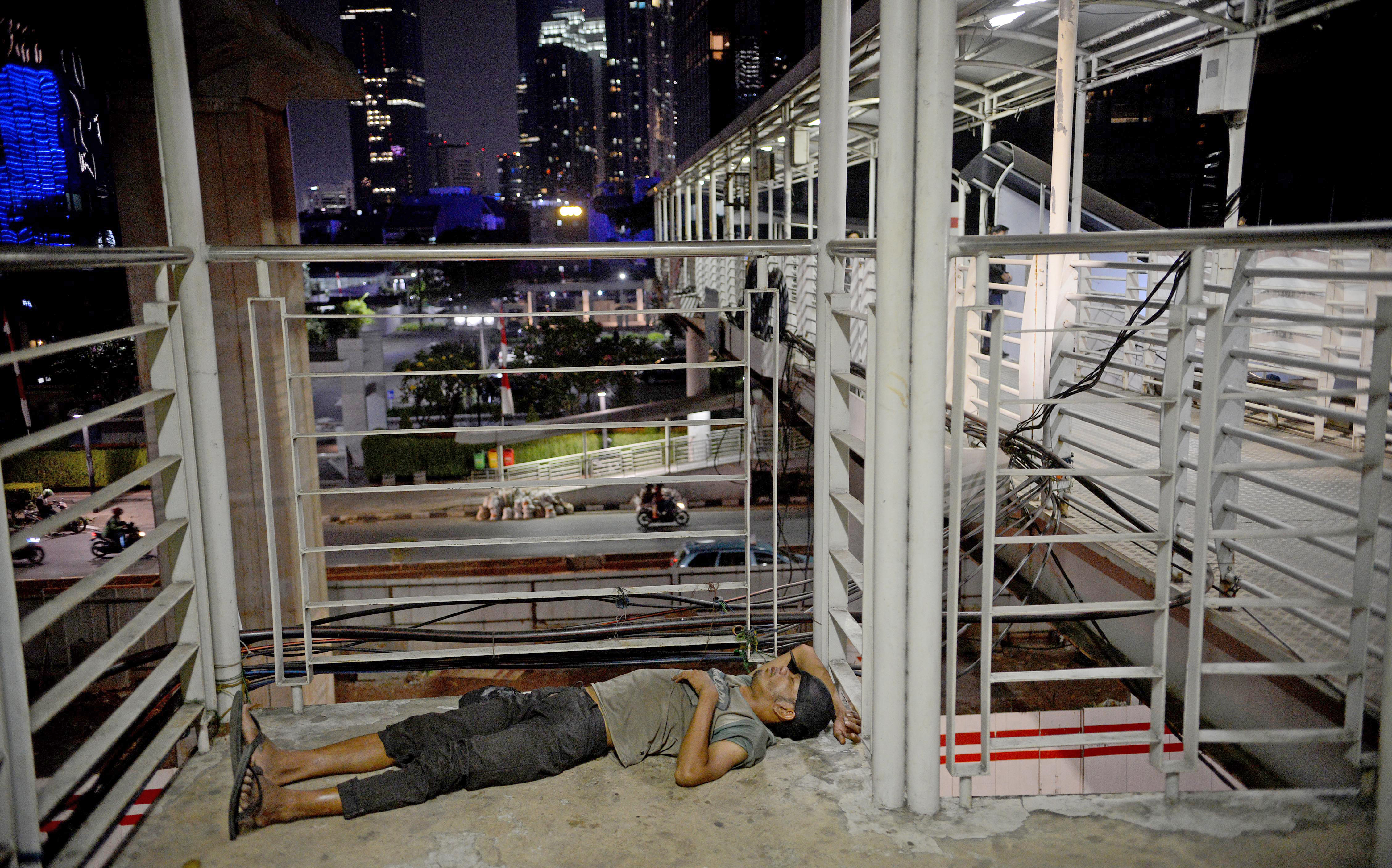 Penyandang Masalah dan Kesejahteraan Sosial (PMKS) beristirahat di jembatan penyeberangan orang di kawasan Rasuna Said, Jakarta, Senin (19/8