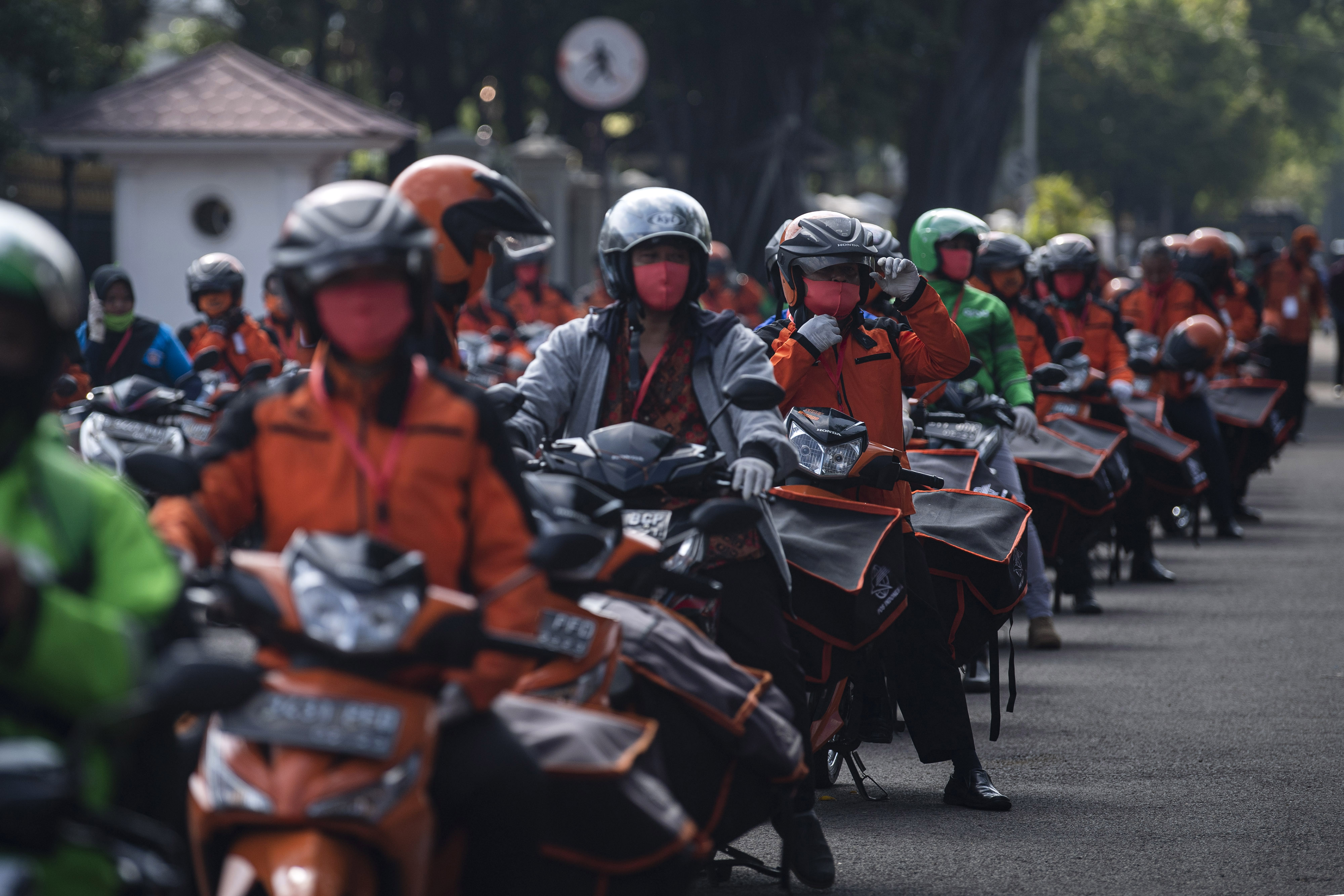 Pegawai PT POS Indonesia (Persero) bersama para ojek daring bersiap mendistribusikan bantuan sosial sembako di depan Istana Merdeka, Jakarta