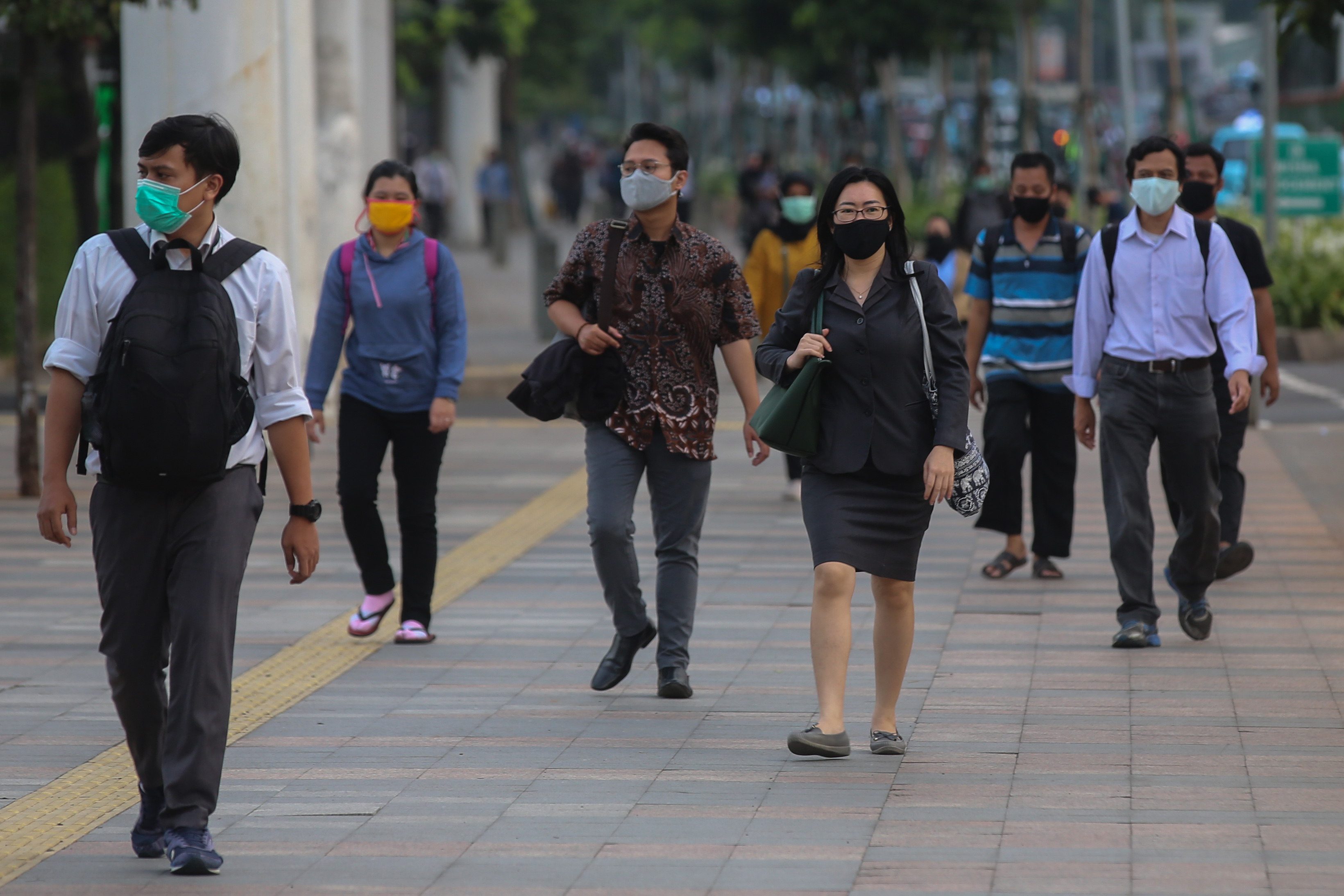 Pekerja melewati trotoar selepas jam kantor di kawasan Sudirman, Jakarta.