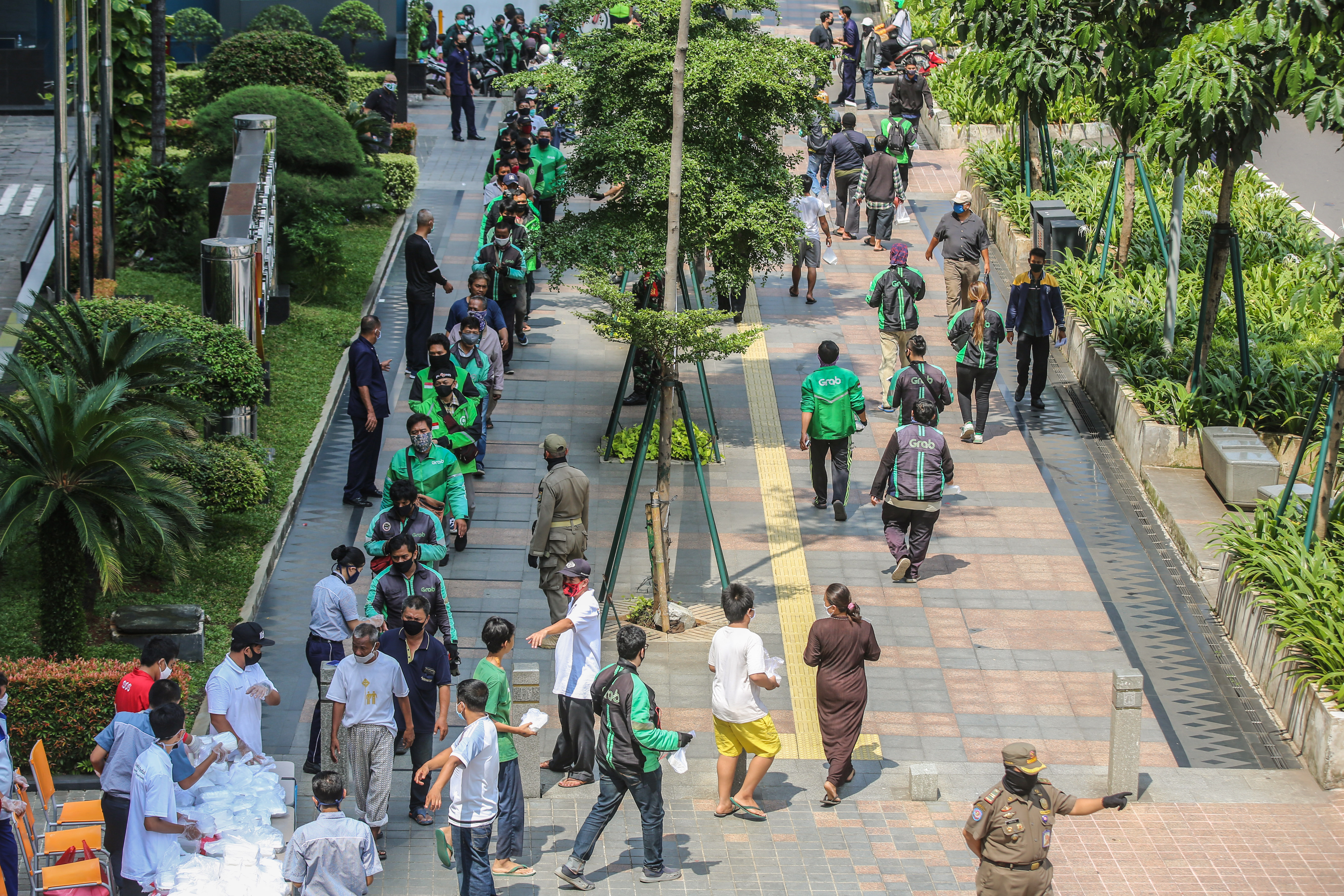 Ojek daring bersama warga antre mendapatkan makan siang yang dibagikan salah satu perusahaan di kawasan Sudirman, Jakarta, Kamis (16/4).