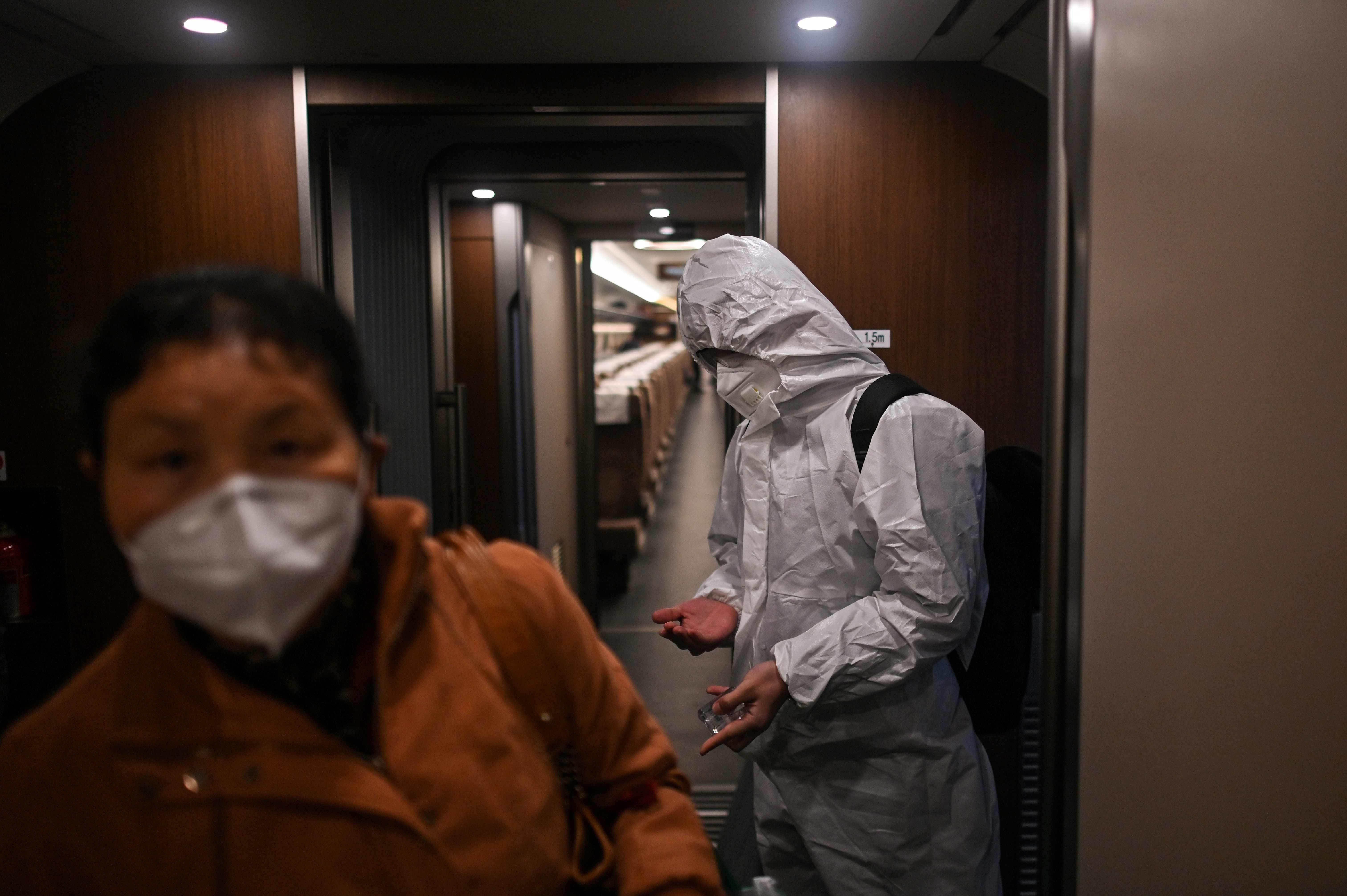 Seorang petugas berbaju hazmat menyemprotkan disinfektan di gerbong kereta di Stasiun Wuhan menuju Shanghai, Senin (20/4/2020).