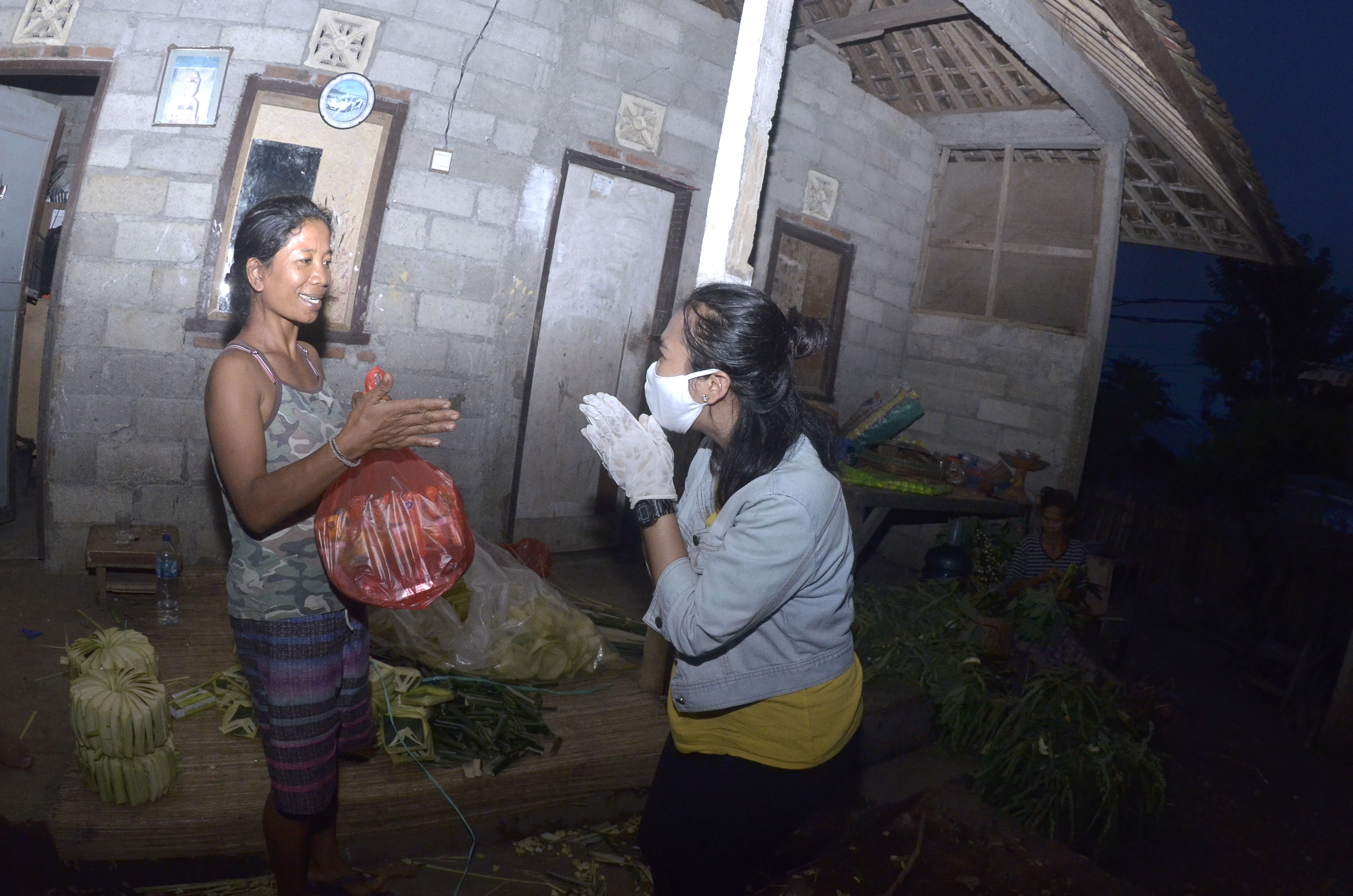 Relawan memberikan paket sembako kepada warga yang membutuhkan di kawasan Jimbaran, Badung, Bali.