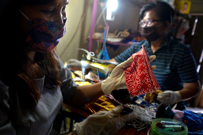 Dua orang pekerja tengah memproduksi masker kain di sebuah tempat usaha di Manado, Sulawesi Utara.