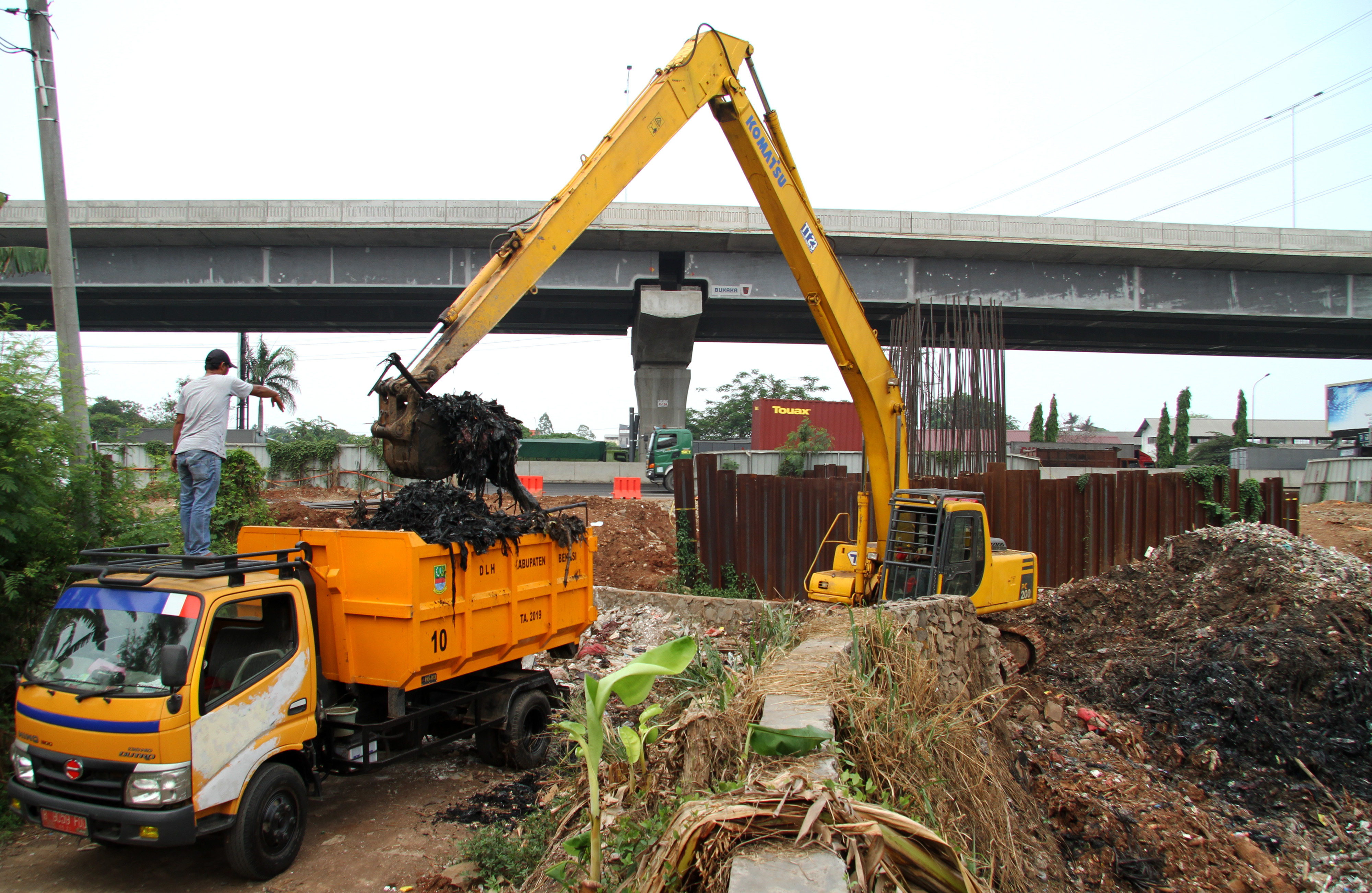 Petugas Dinas Lingkungan Hidup sedang mengangkat sampah di Kali Jambe Bekasi
