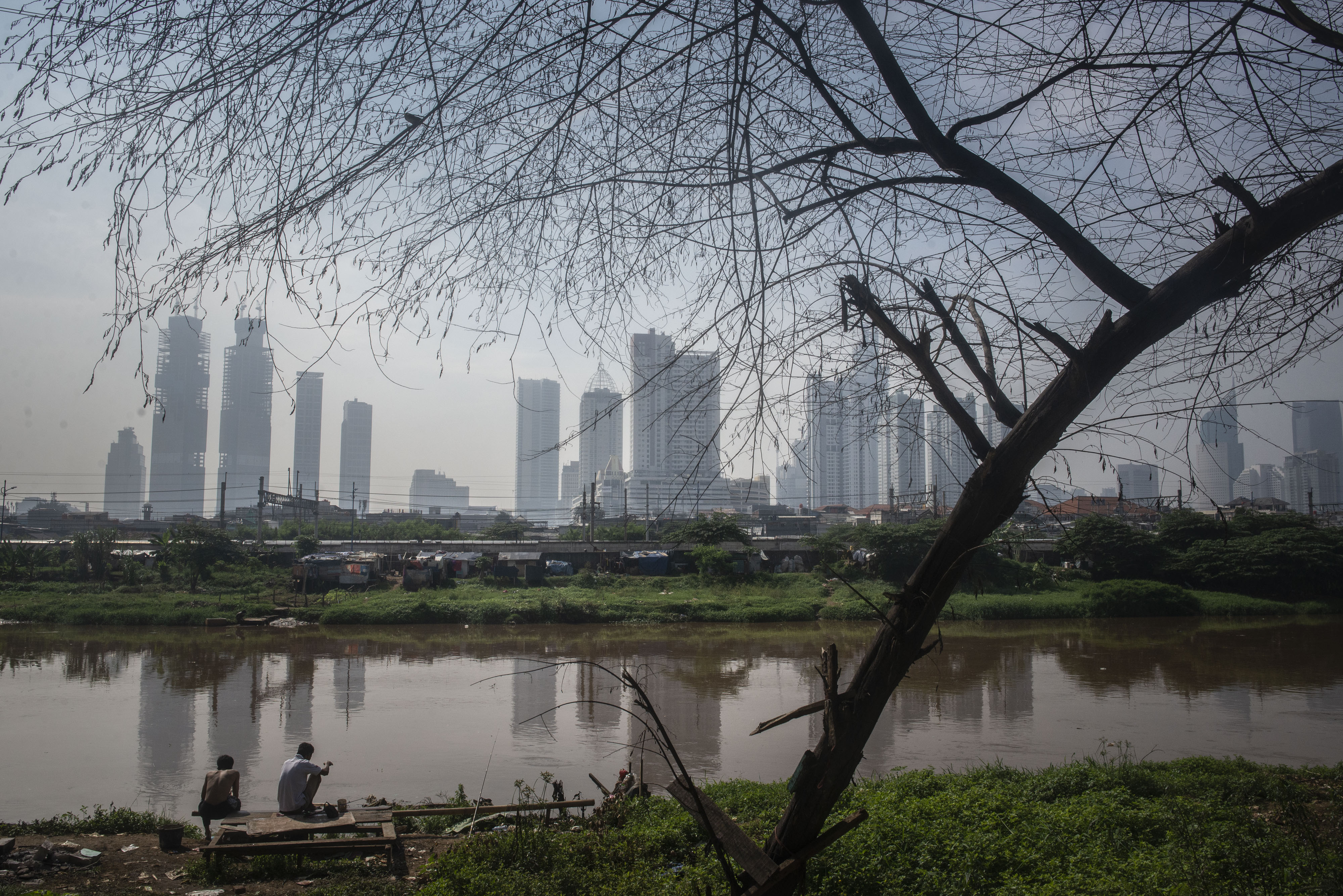 Warga beraktivitas dengan latar belakang gedung pencakar langit.