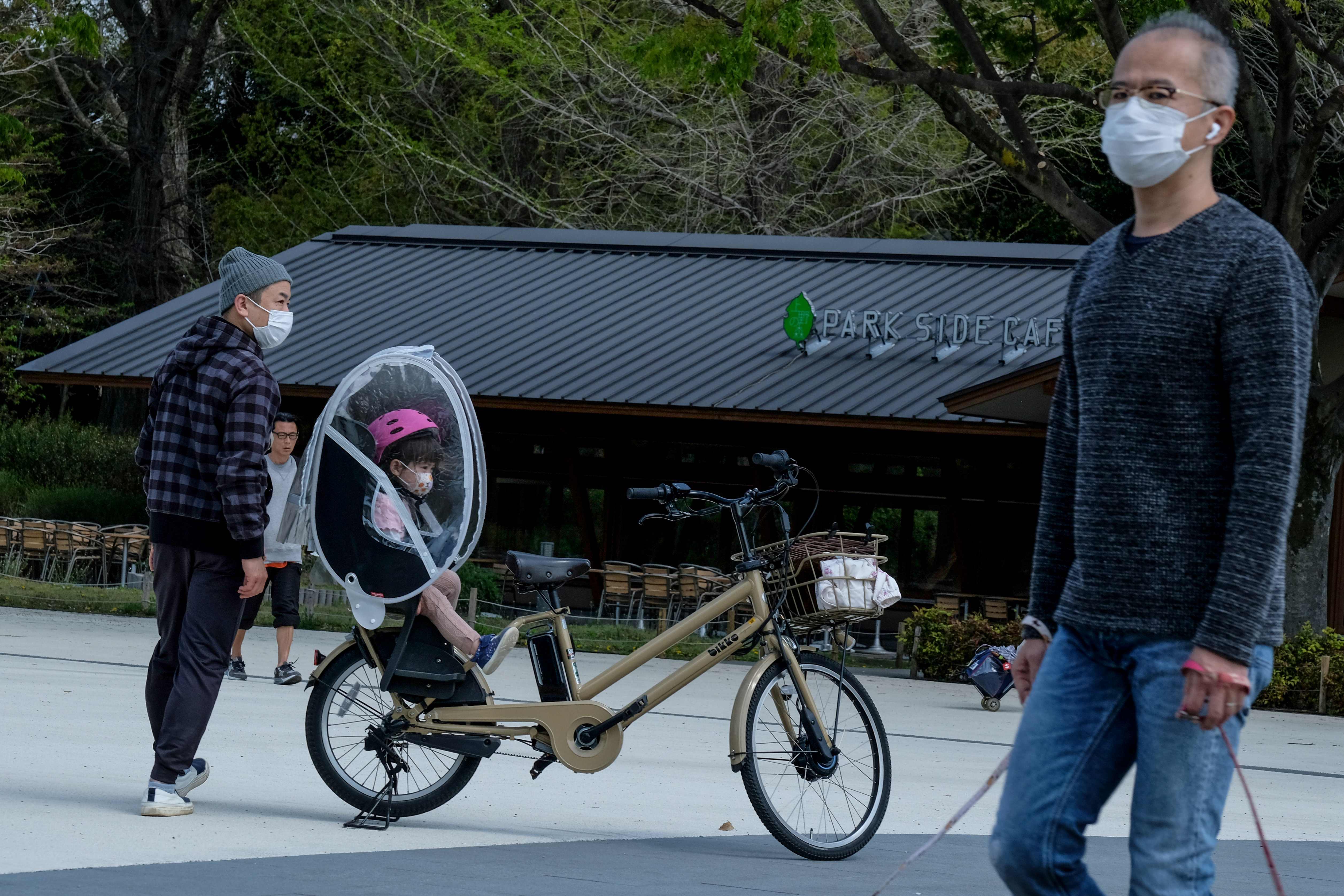 Dengan mengenakan masker, warga Jepang berjalan di Taman Ueno, Tokyo.