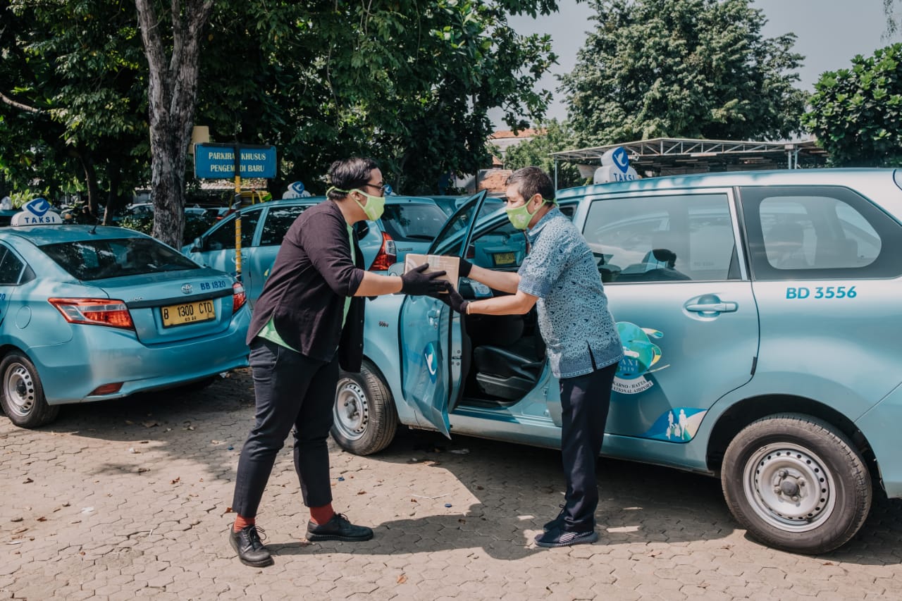 Seorang relawan membagi-bagikan bingkisan berupa nutrisi kepada sejumlah sopir taksi.