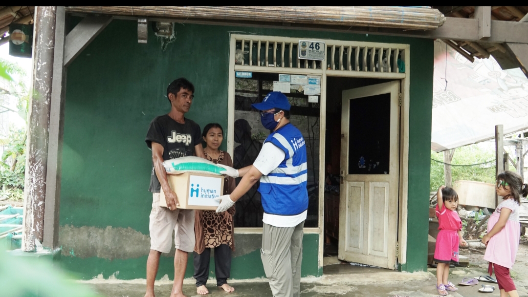 Relawan human initiative membagikan paket sembako ke warga