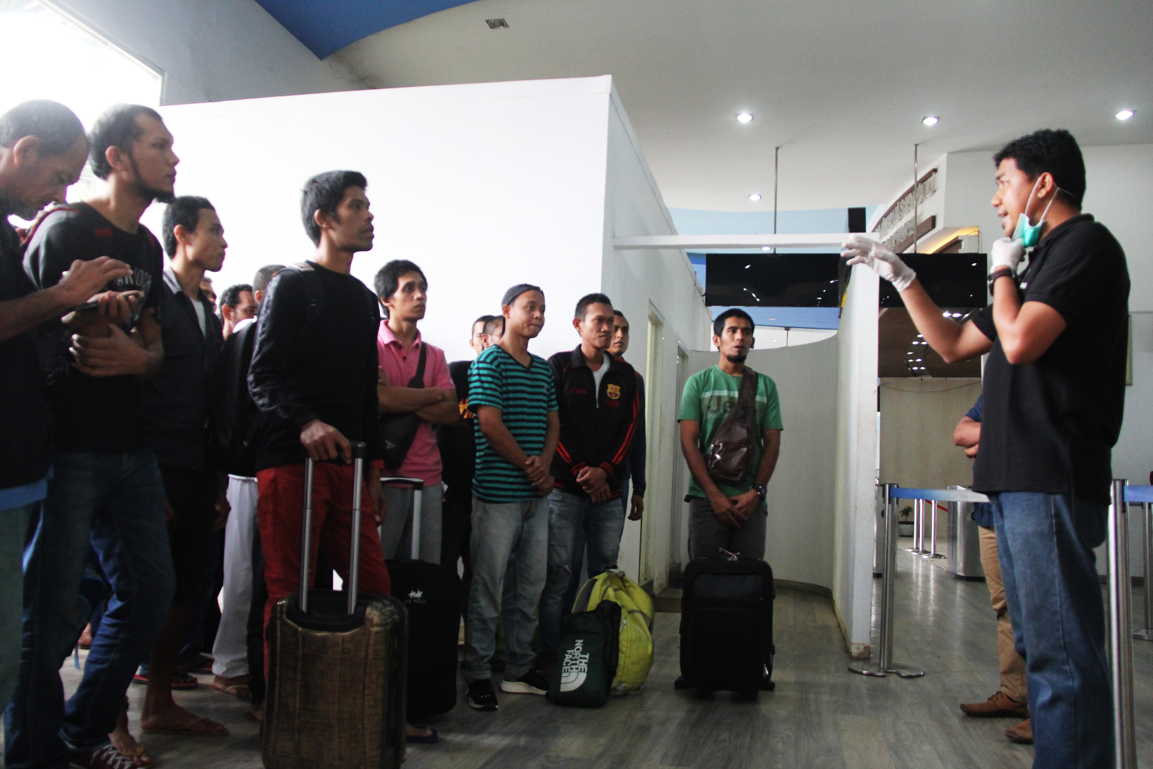 Seorang petugas otoritas perlindungan tenaga kerja memberikan pengarahan kepada pekerja migran yang dipulangkan dari Malaysia.