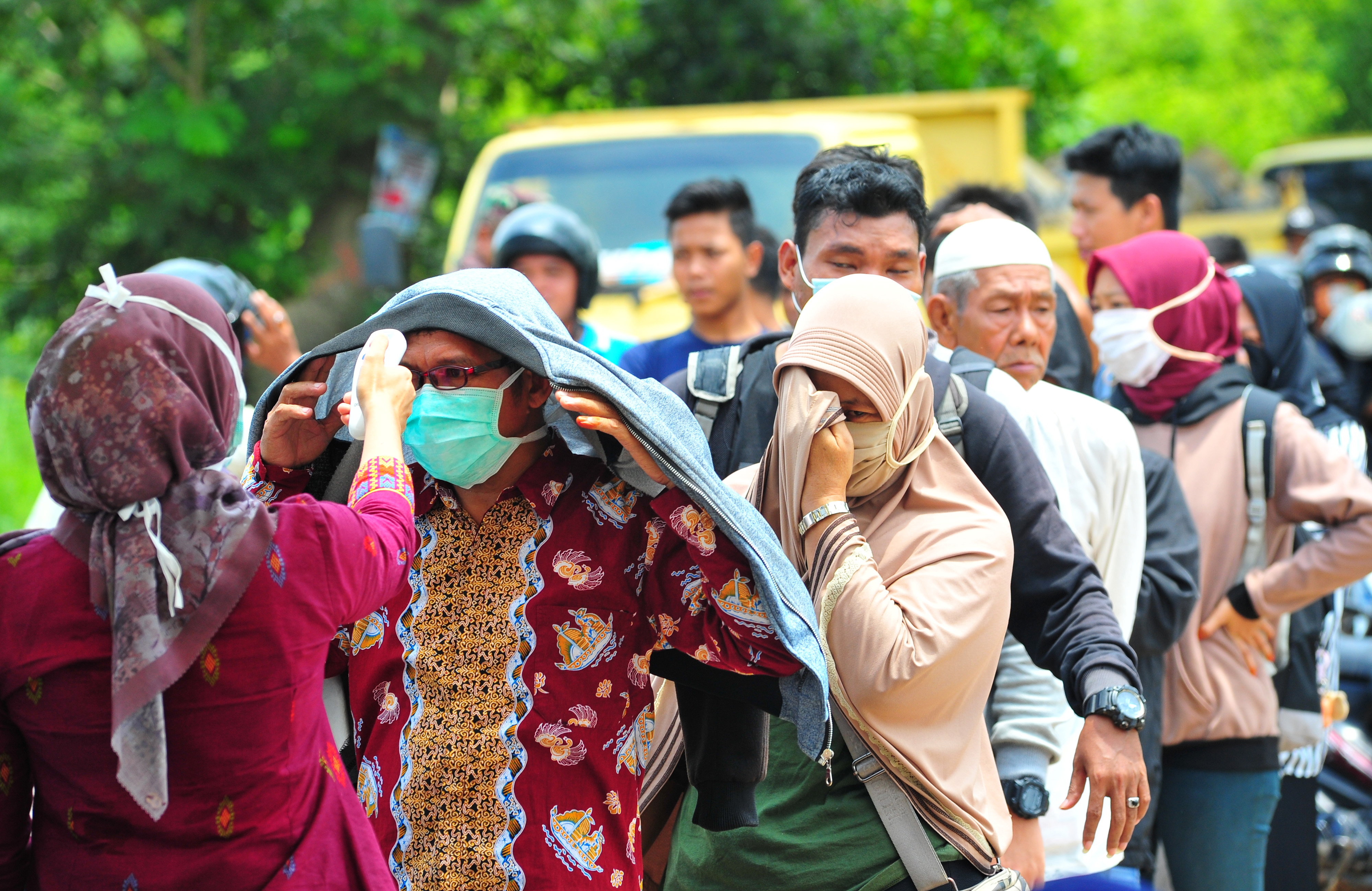 Petugas kesehatan mengecek suhu tubuh warga yang akan melakukan perjalanan dan memasuki Kota Jambi dari Kabupaten Muarojambi.