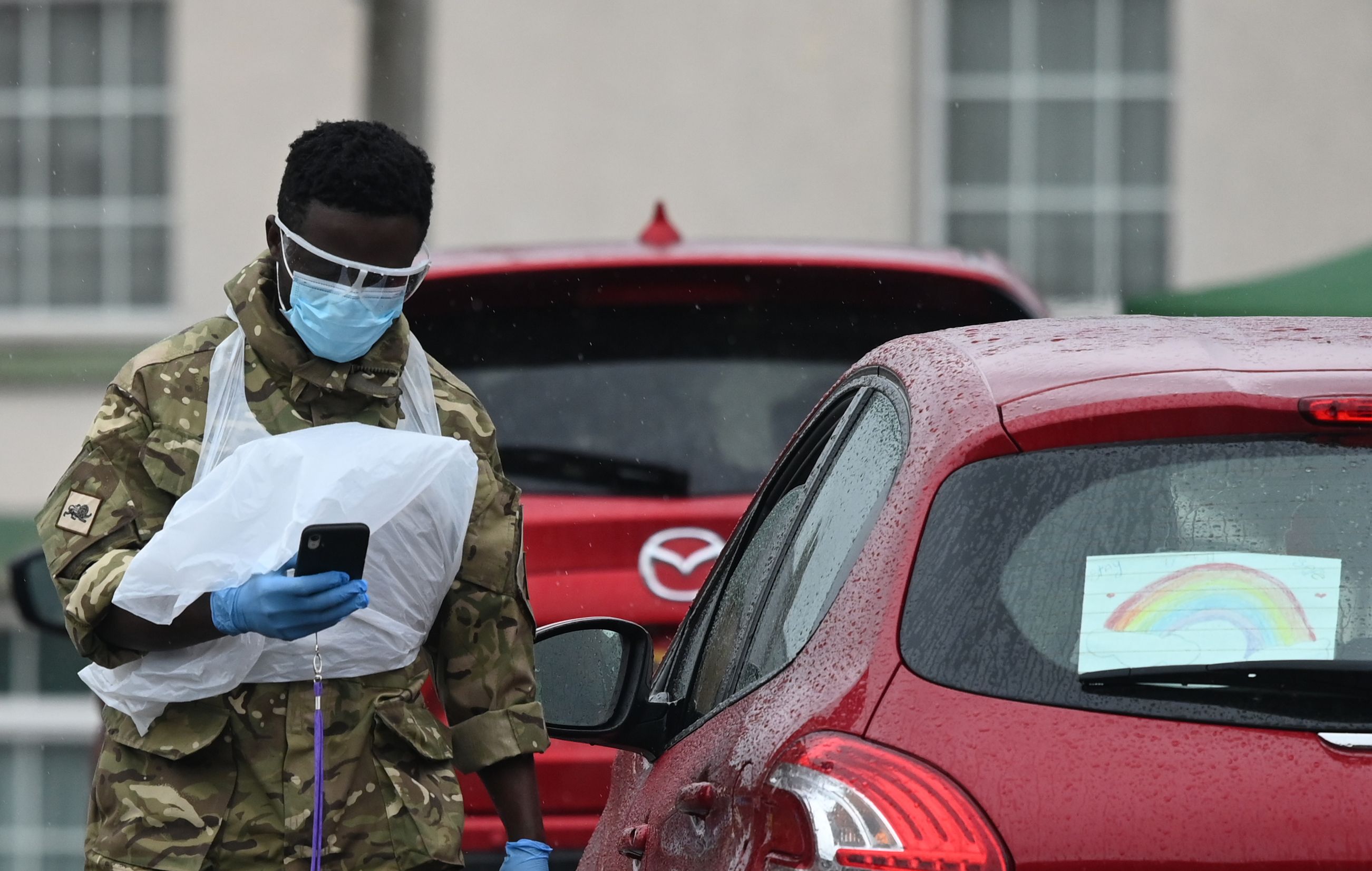 Personel militer mengarahkan warga yang akan melakukan tes covid-19 secara drive-in di Macclesfield, Inggris.