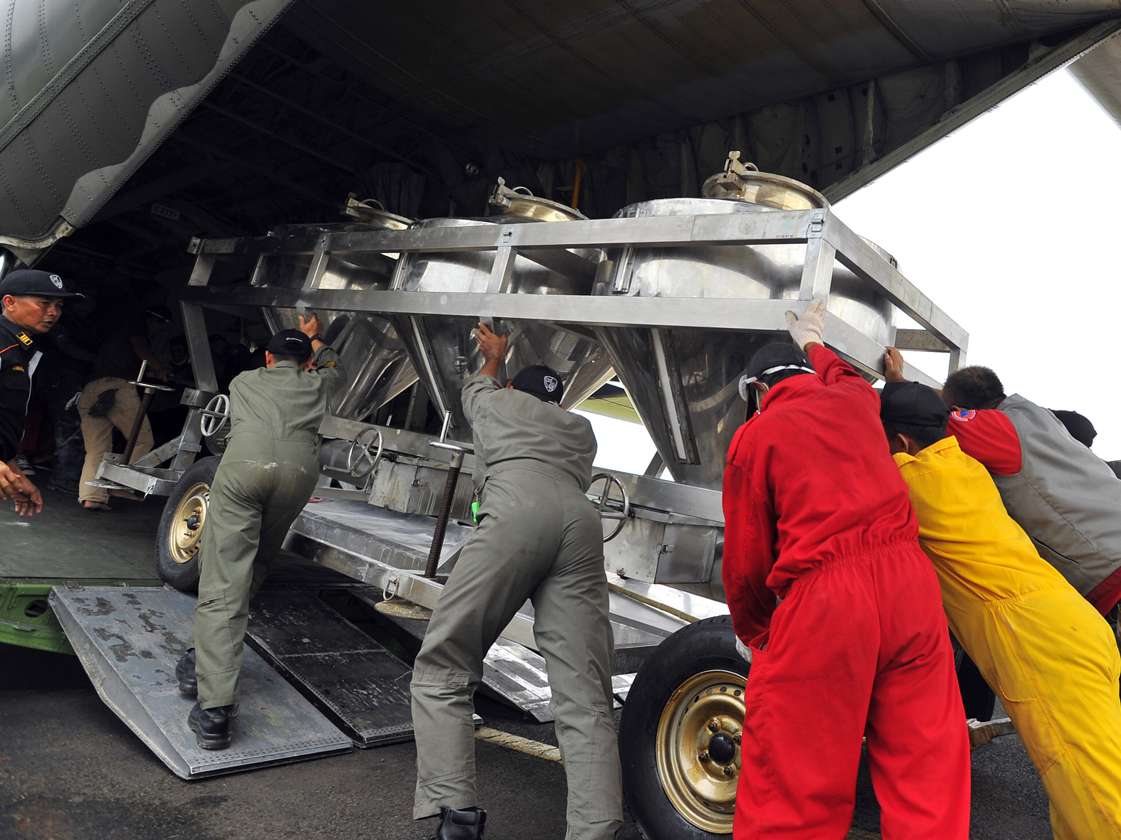 Sejumlah petugas membawa tangki berisi garam untuk dinaikkan ke pesawat Hercules C-130 di Lanud Halim Perdana Kusuma Jakarta, (15/3).