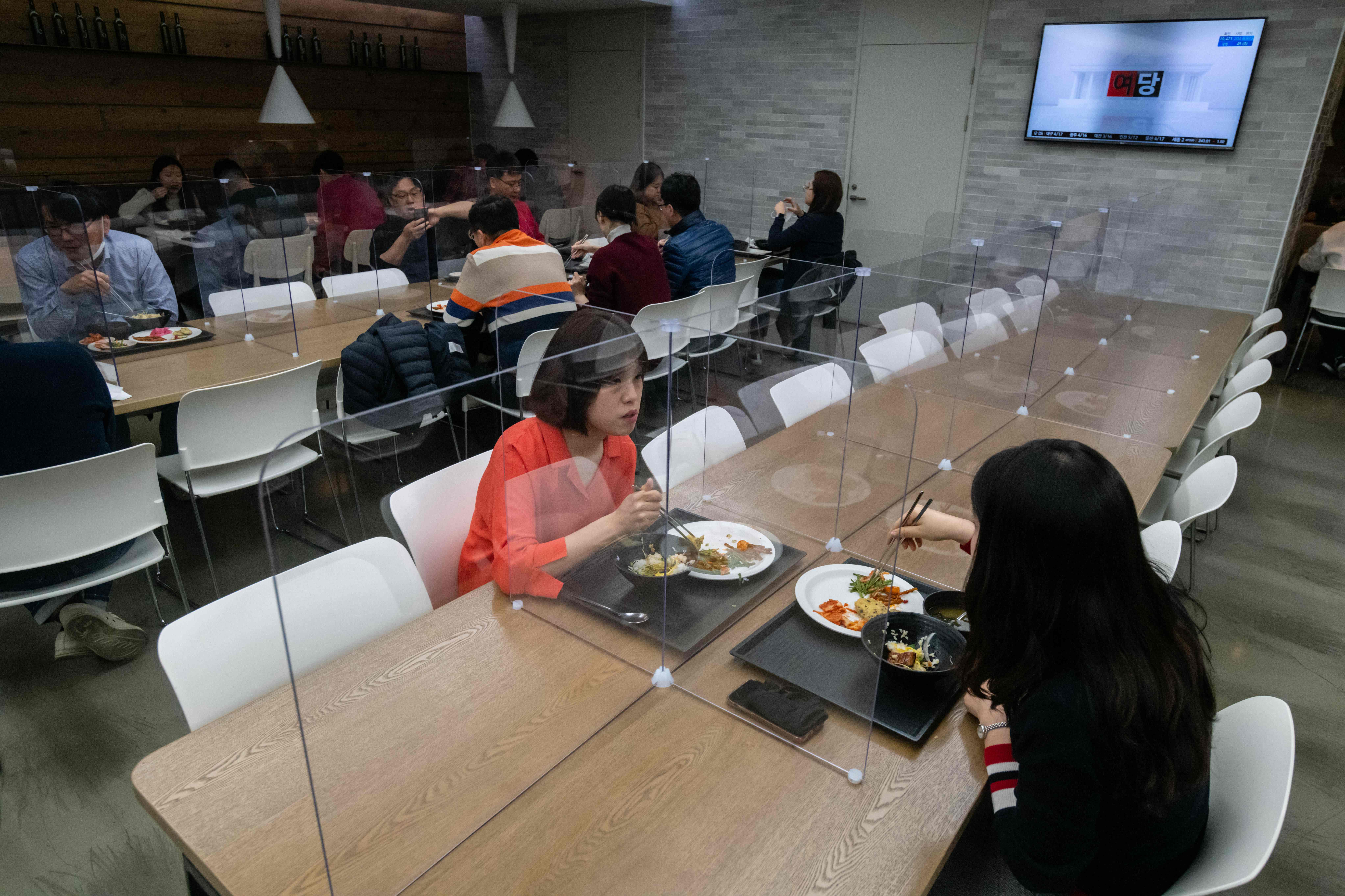 Pekerja makan di sebuah cafetaria di Seoul, Korsel yang dilengkapi layar penghalang untuk mencegah menyebaran covid-19.