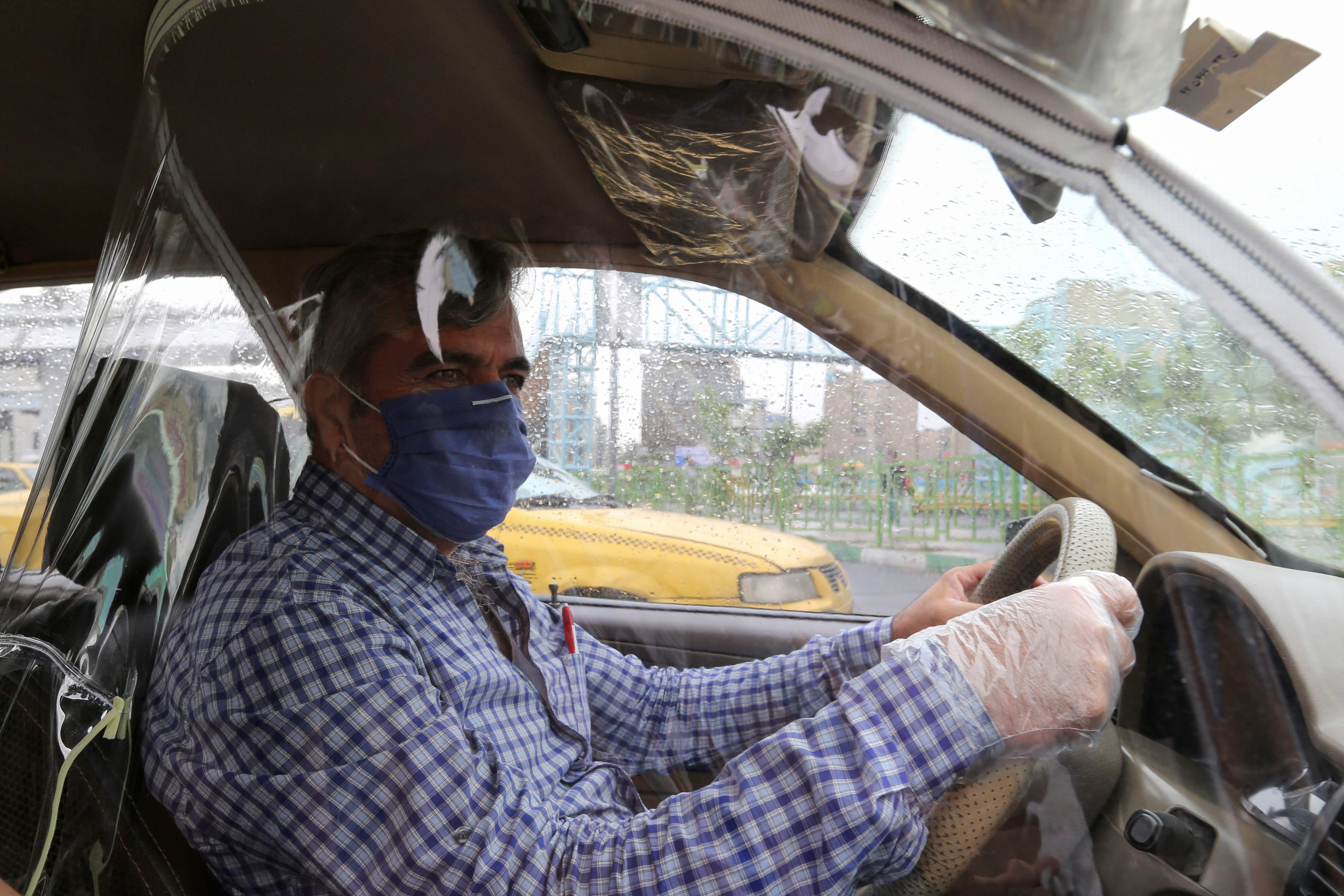 Supir taksi di Iran memasang layar transparan untuk mengisolasi dirinya dari penumpang demi menghindar dari tertular covid-19.