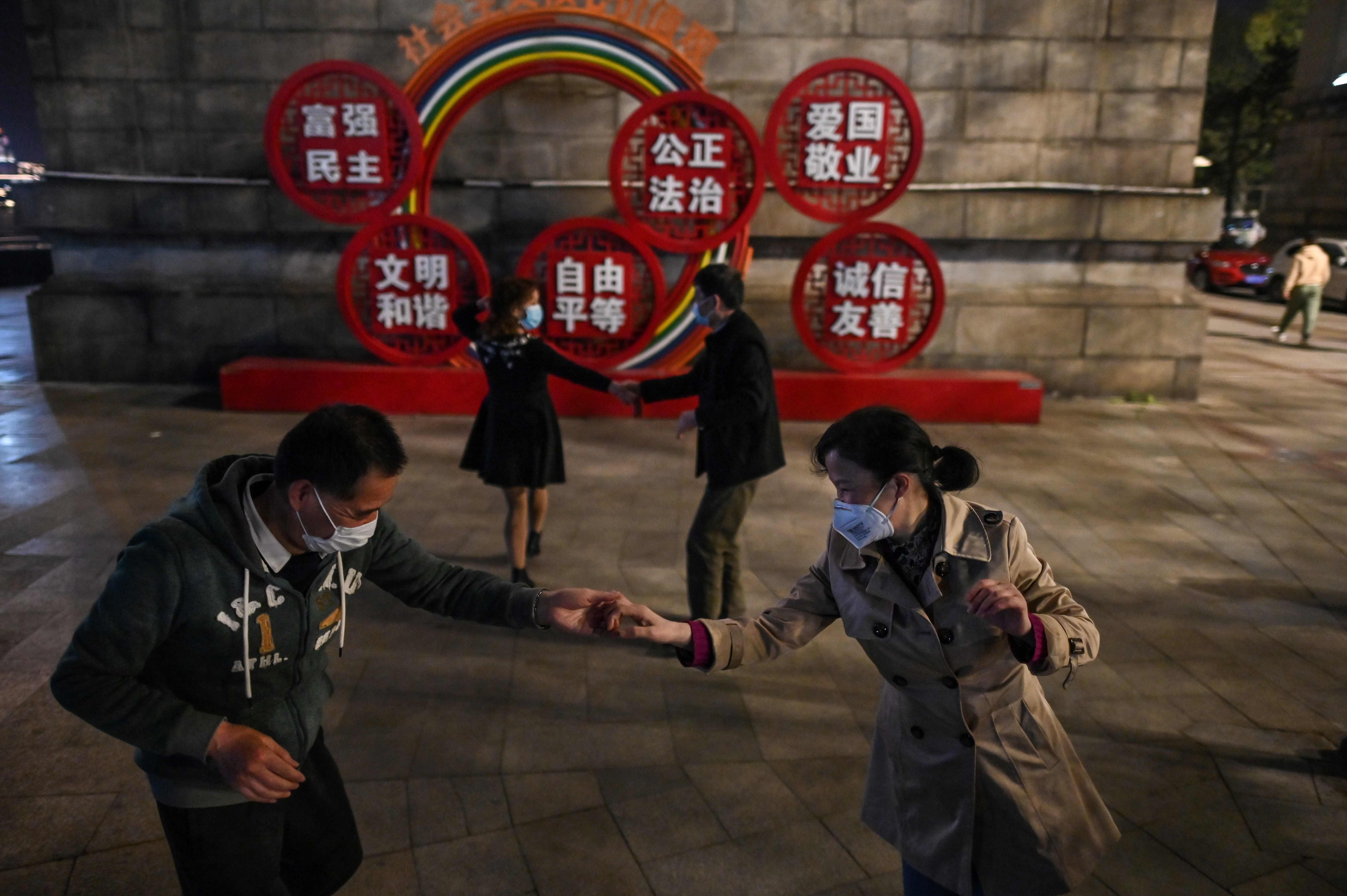 Warga Tiongkok mengenakan masker berdansa di tepi Sungai Yangtze, Wuhan.