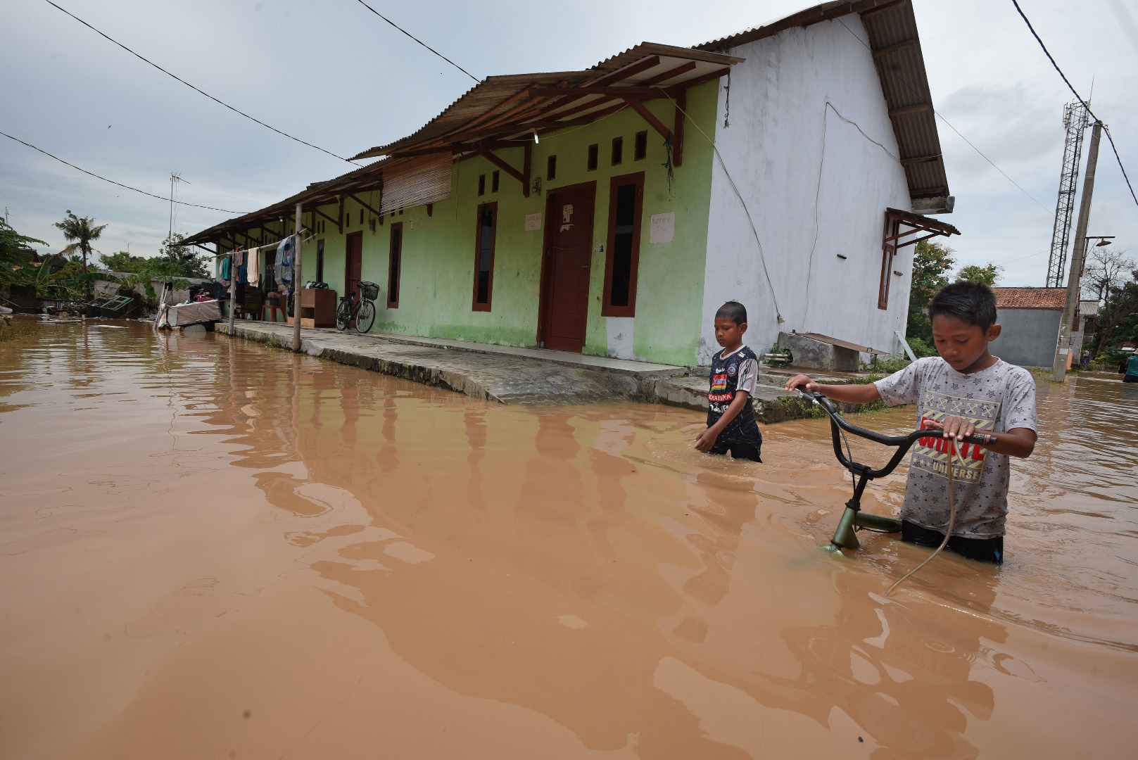 Dua anak kecil melintasi banjir di Kampung Margasana, Serang, Banten.