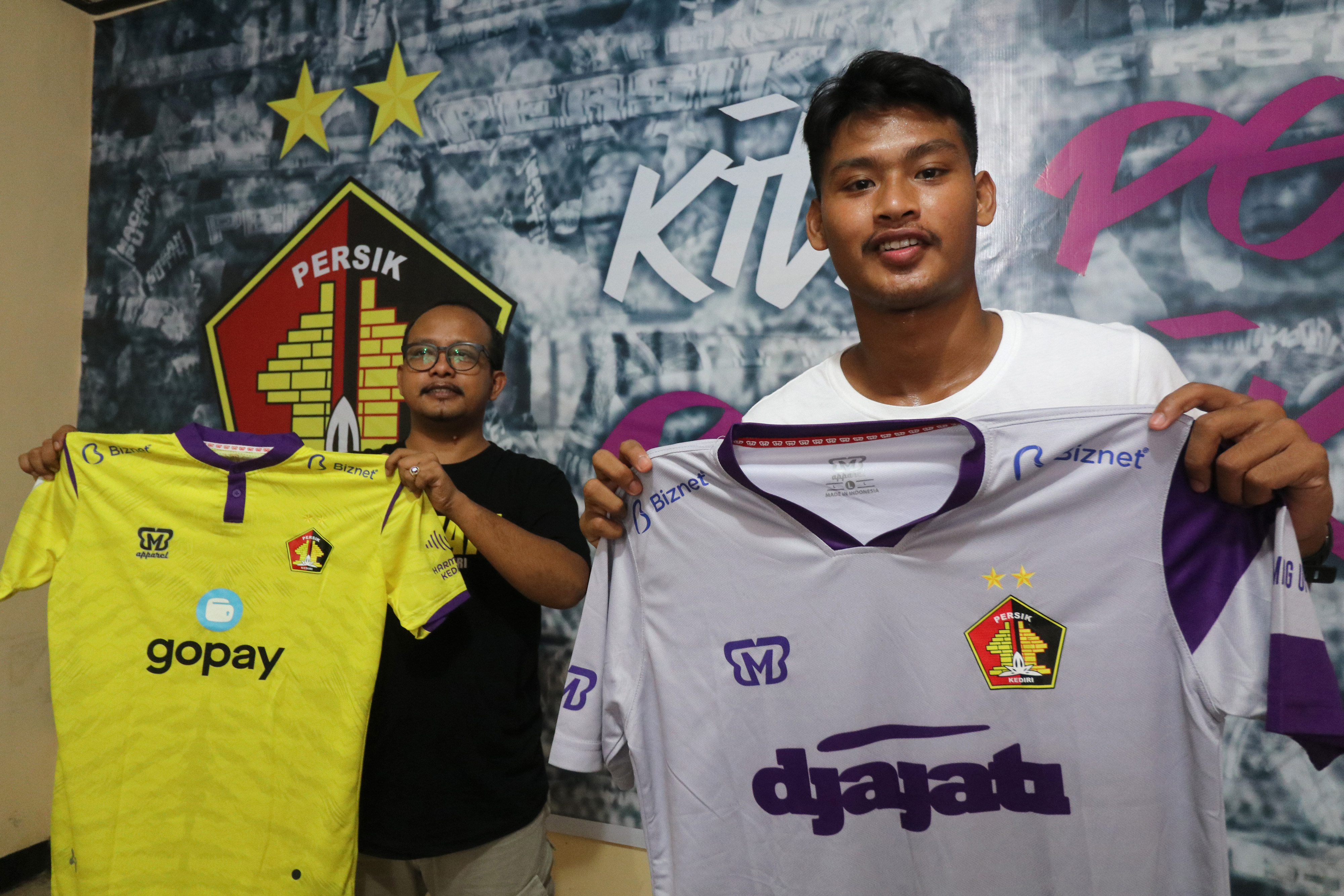 Pesepak bola Persik Kediri Septiap Bagaskara (kanan) memegang jersey miliknya sebelum diserahkan kepada pemenang lelang Reza Mardianto (kiri