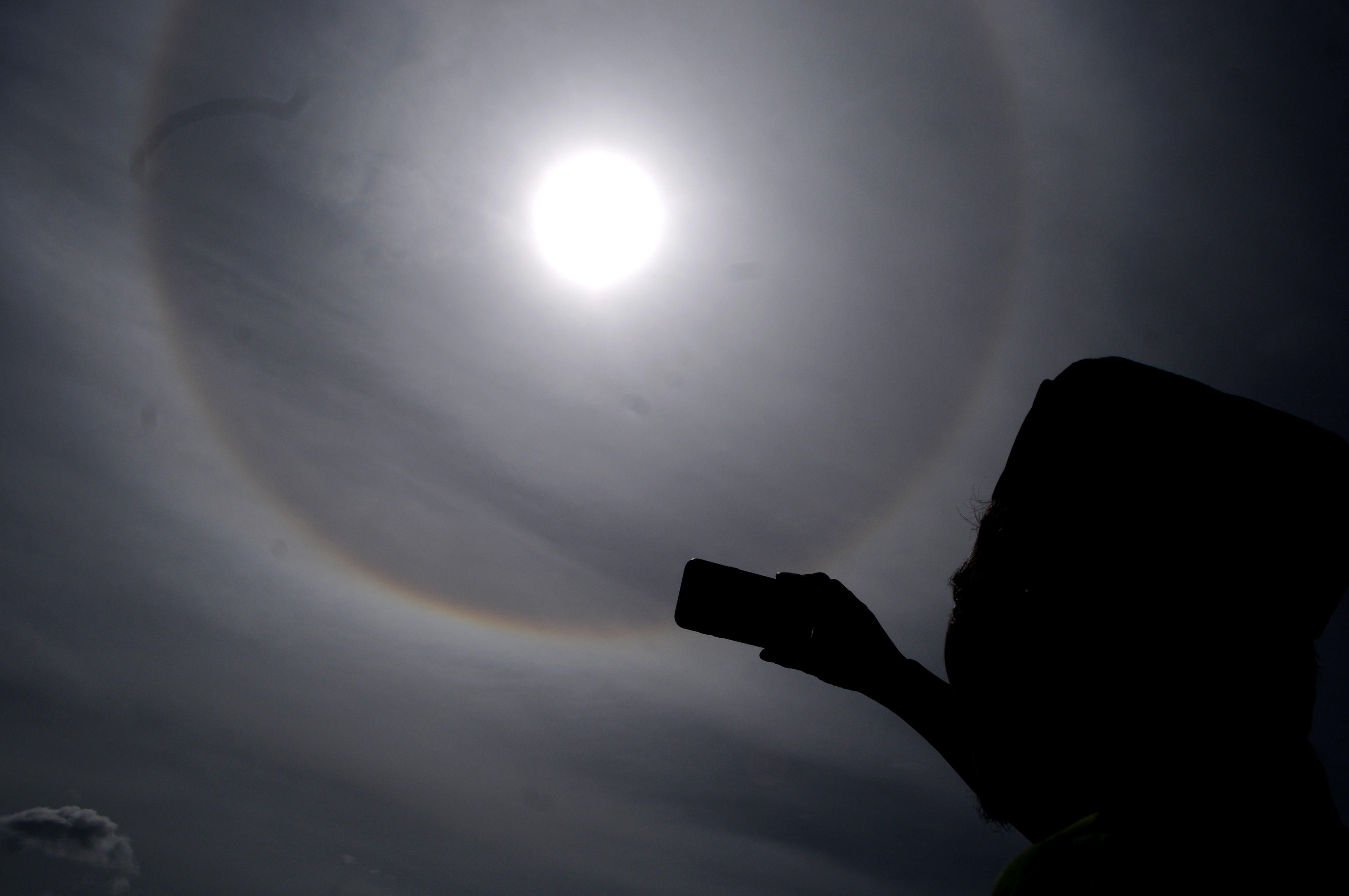 Seorang warga mengabadikan fenomena halo matahari.