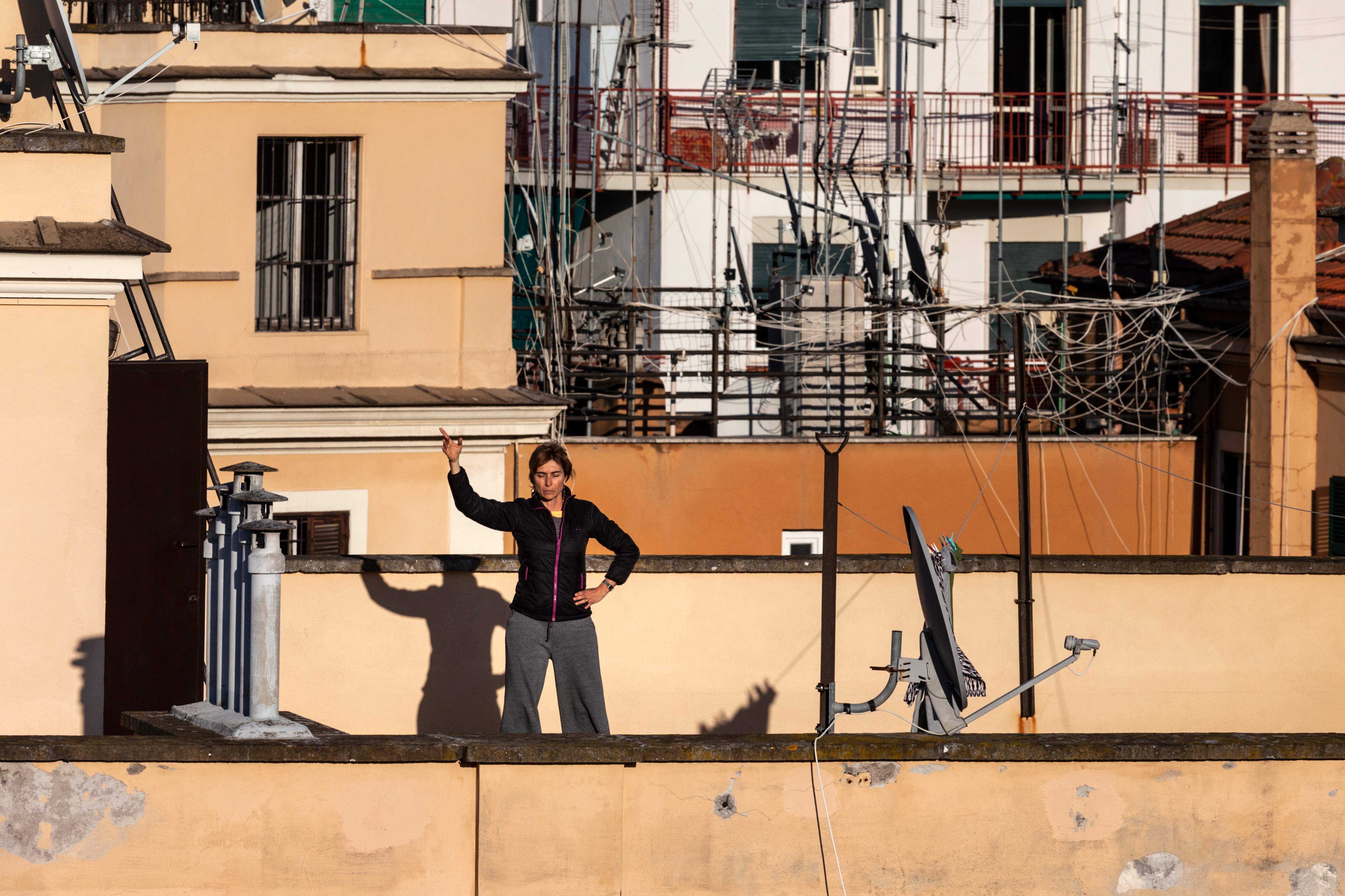 Seorang perempuan berolahraga di atap bangunan perumahannya di Roma, Italia saat negara itu memberlakukan lockdown.